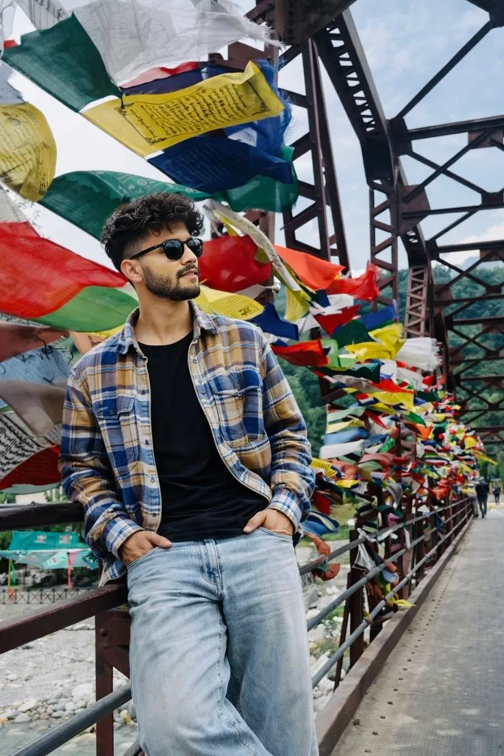 A photorealistic vertical medium-full shot of the young South Asian man from the reference image, faithfully preserving his exact