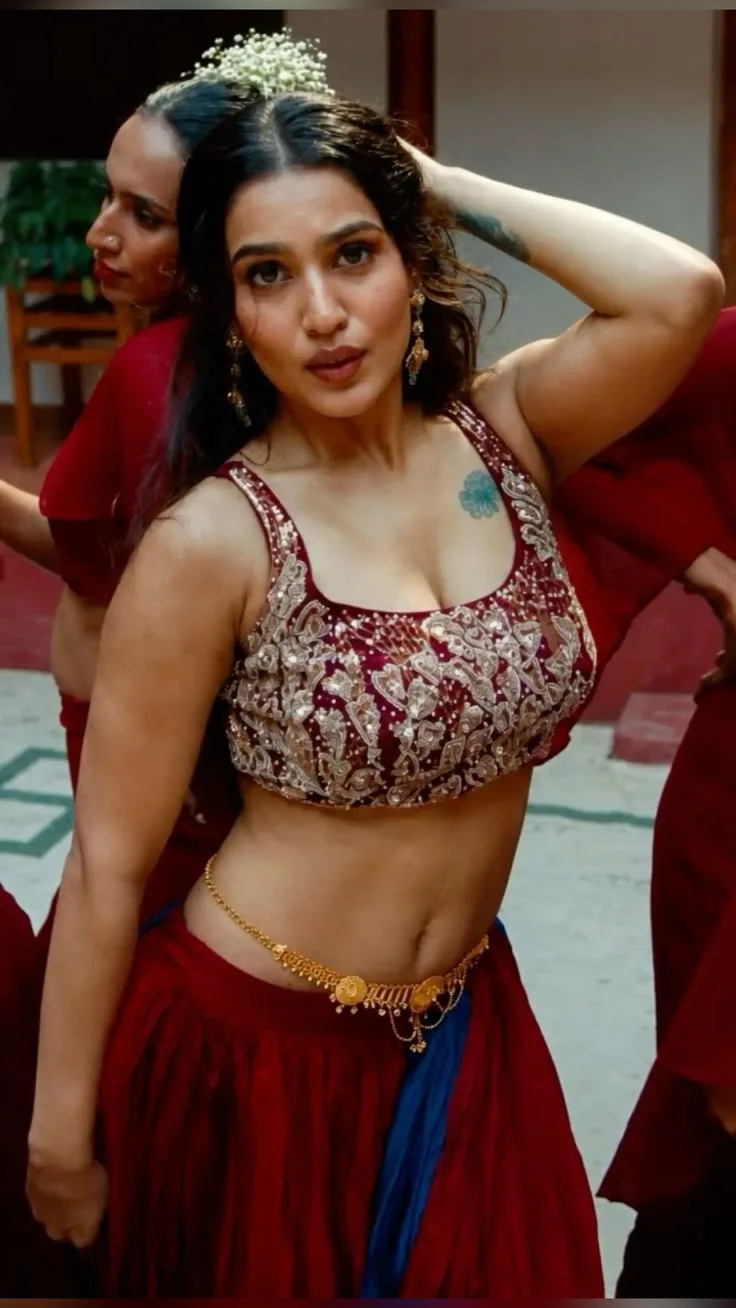 A photorealistic Indian woman performing a graceful traditional dance pose, wearing an elegant deep maroon and royal blue traditional