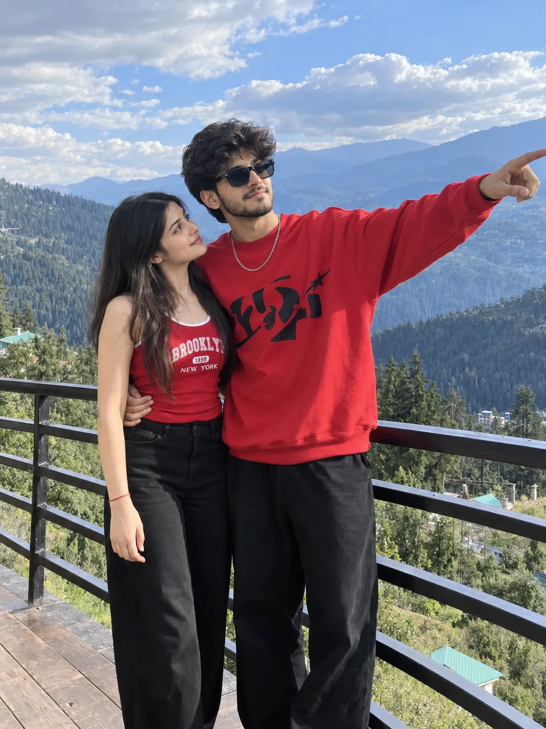 A photorealistic, candid smartphone photograph of a young couple on a scenic mountain balcony, shot in a 3:4 vertical medium framing