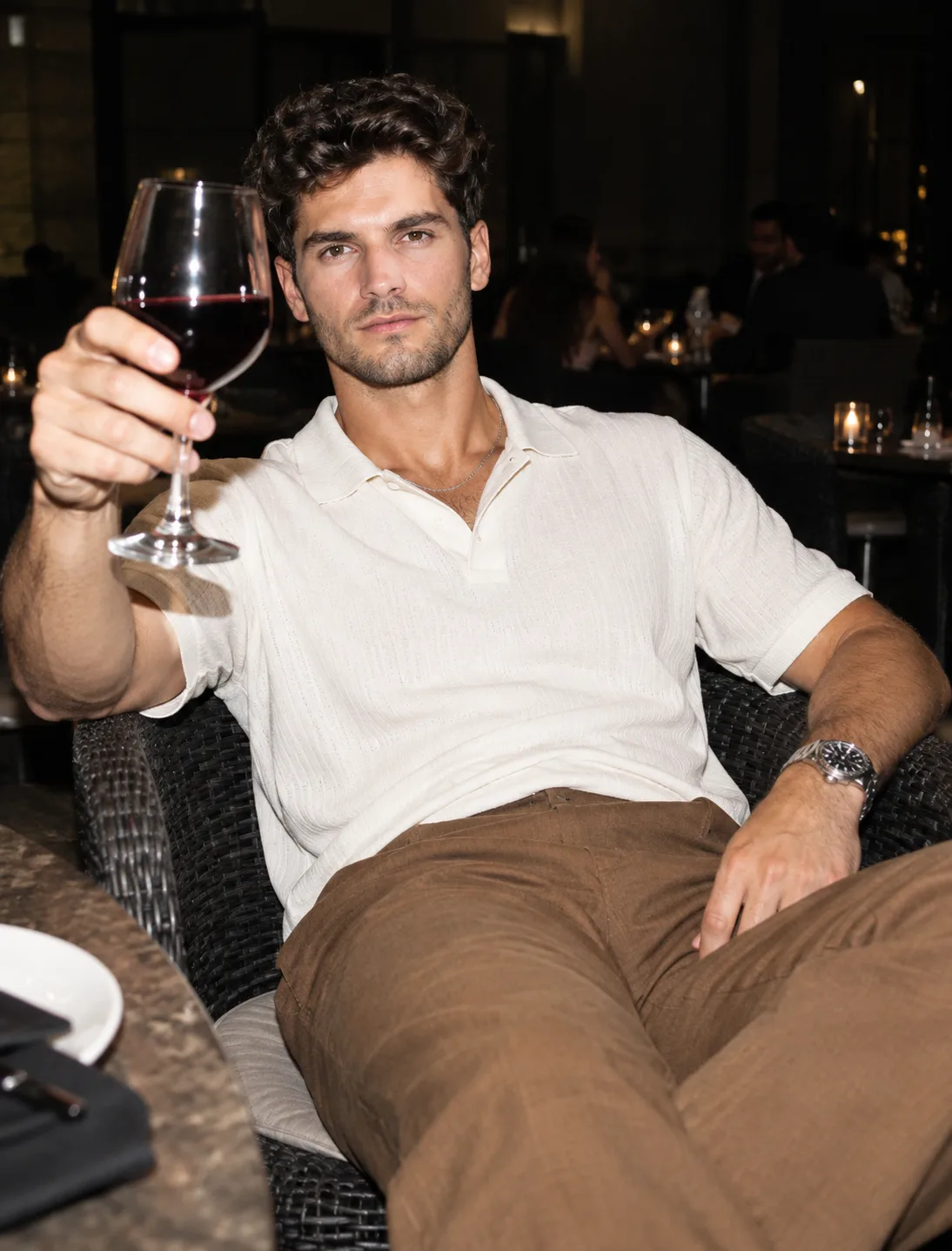 Create a photo of a man (reference uploaded image) sitting in a restaurant chair.