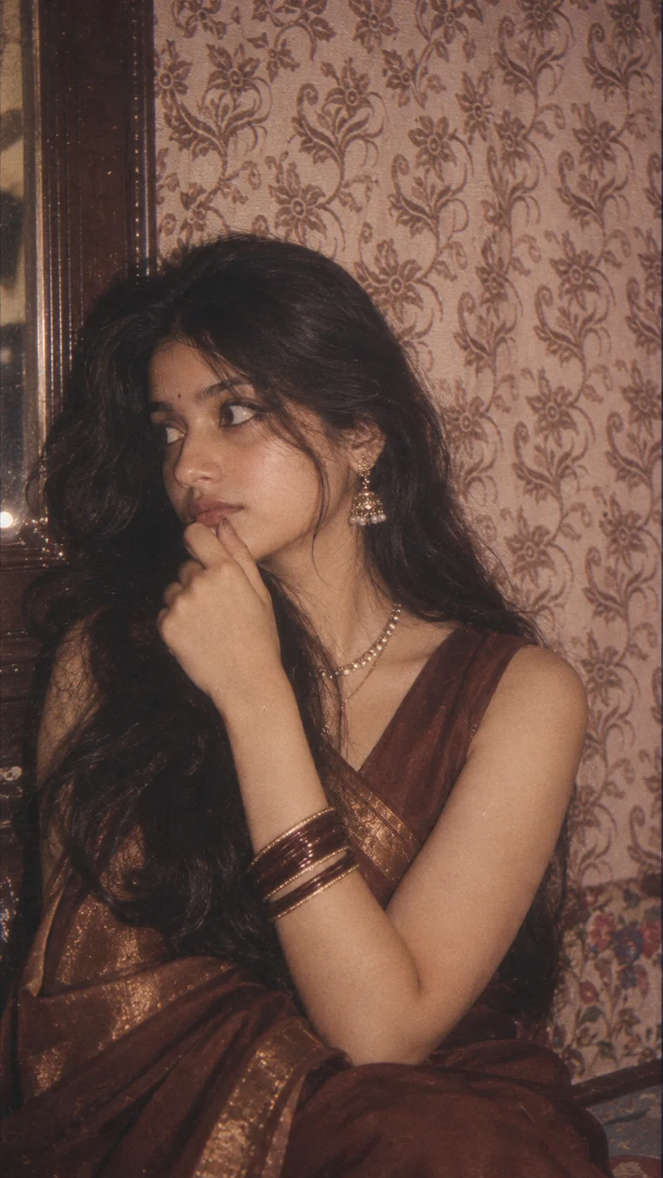 Prompt: Create a highly realistic vertical 9:16 vintage portrait of a young Indian woman sitting indoors, inspired by the uploaded