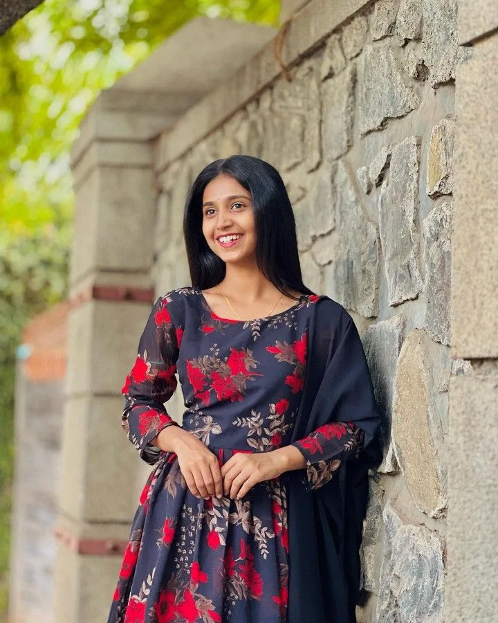 A photorealistic vertical medium shot of the young South Asian woman from the reference image, faithfully preserving her recognizable