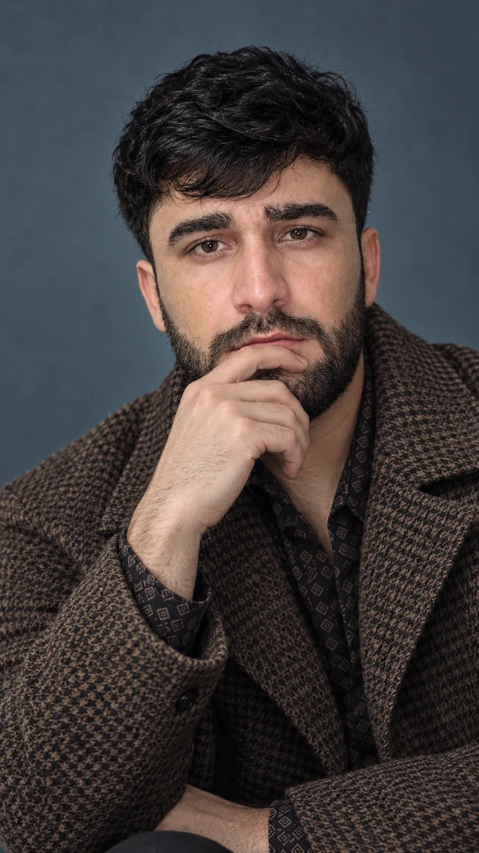 Ultra-realistic high-end cinematic close-up portrait of a handsome young man wearing a sophisticated oversized brown houndstooth wool