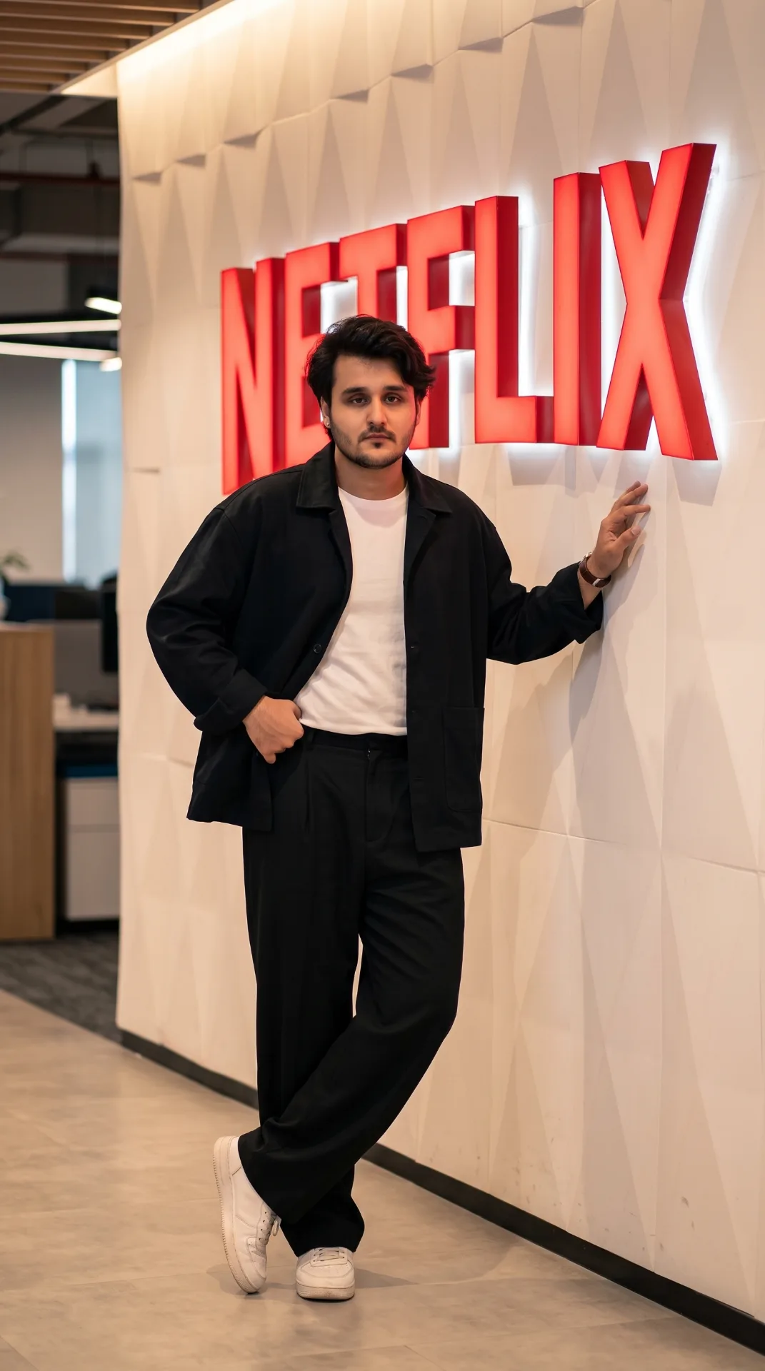 Ultra-realistic cinematic Netflix office portrait of a tall South Asian man standing confidently beside the iconic red Netflix logo on a