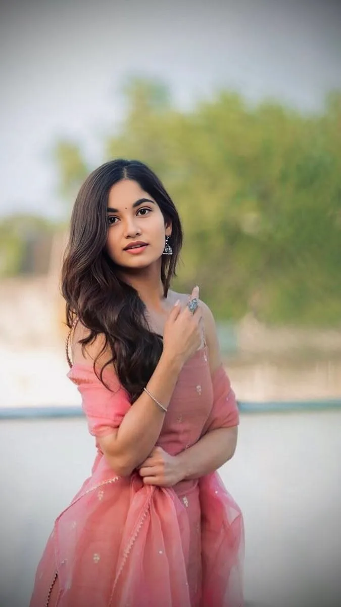 A photorealistic vertical medium shot of the young South Asian woman from the reference image, faithfully preserving her recognizable