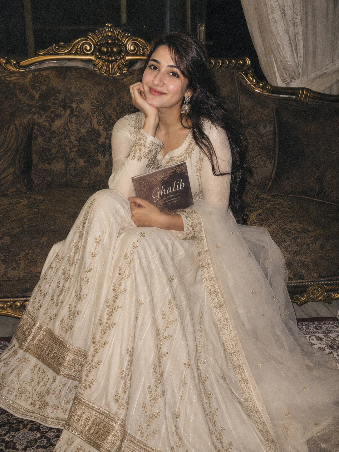 Same person as the reference image, same identity, I'm sitting on a royal sofa, smiling while looking at the camera, a book named "ghalib "