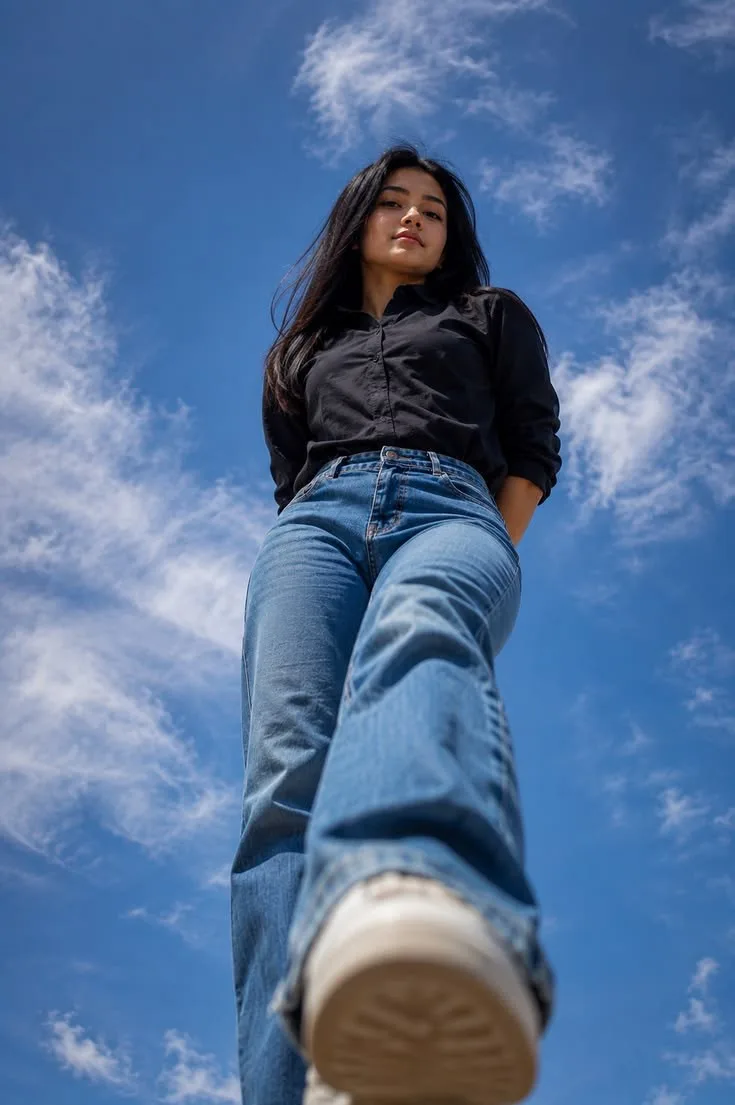 Create a highly realistic, cinematic low-angle full-body outdoor portrait of a stylish young Indian woman, photographed from an extreme