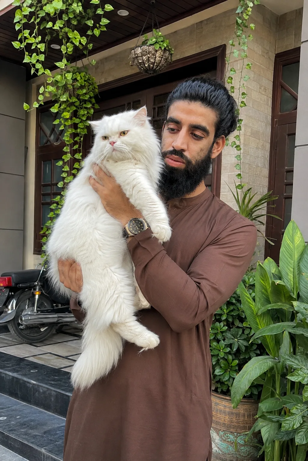 Create an ultra-photorealistic high-resolution lifestyle portrait of an adult South Asian man standing outside a beautiful upscale Indian