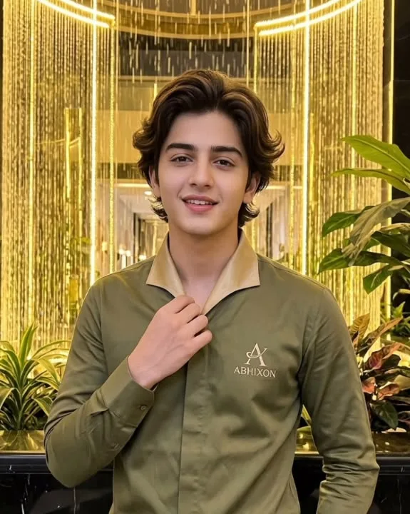 A high-quality medium shot of a charming young teenage boy with neatly styled, voluminous wavy curtain-style brown hair and a warm smile.