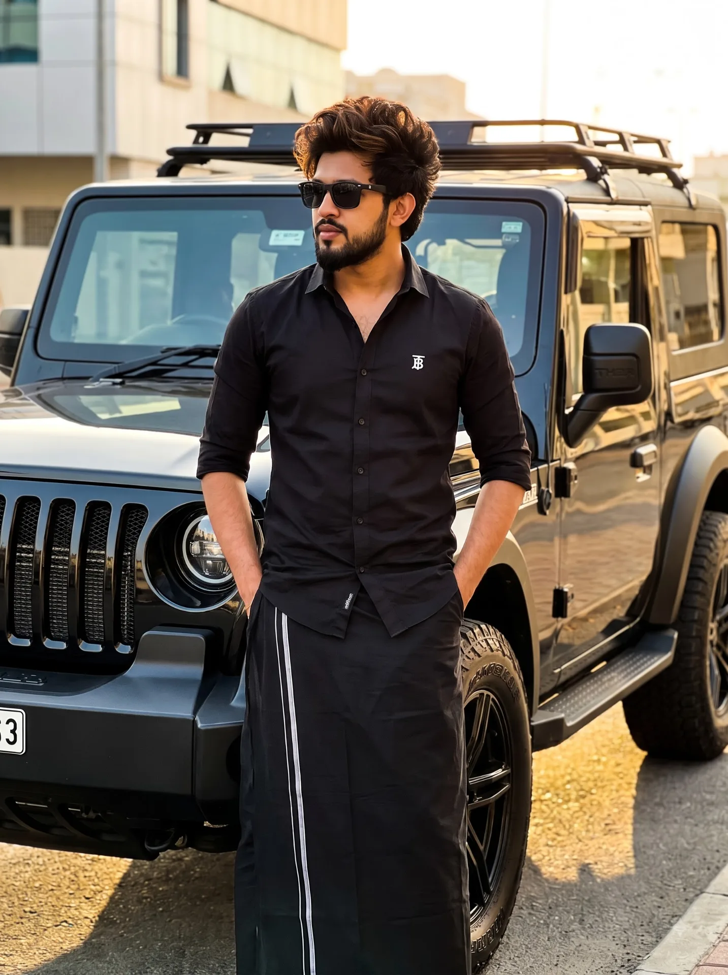 Ultra-realistic full-body cinematic portrait of a stylish young South Asian man standing casually in front of a glossy black modified