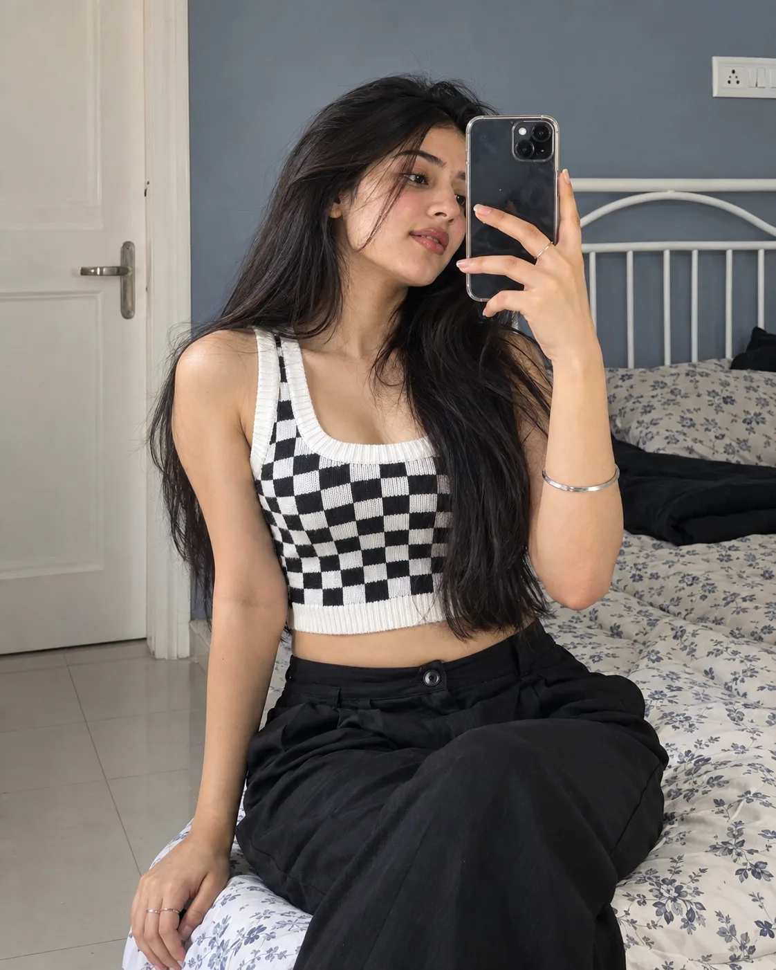 Create an ultra-photorealistic vertical DSLR-style bedroom selfie portrait of a young adult South Asian woman seated casually on the edge