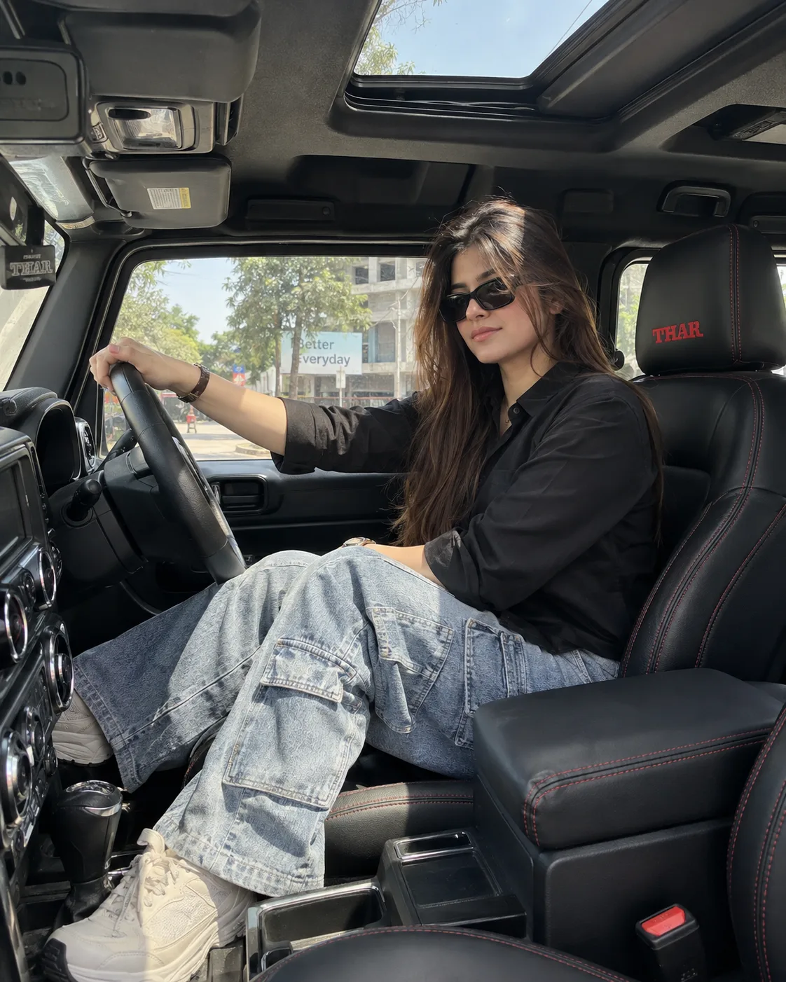 A candid, high-quality photograph taken from inside a black Mahindra Thar SUV, focusing on the same young woman seen in image 0 and image