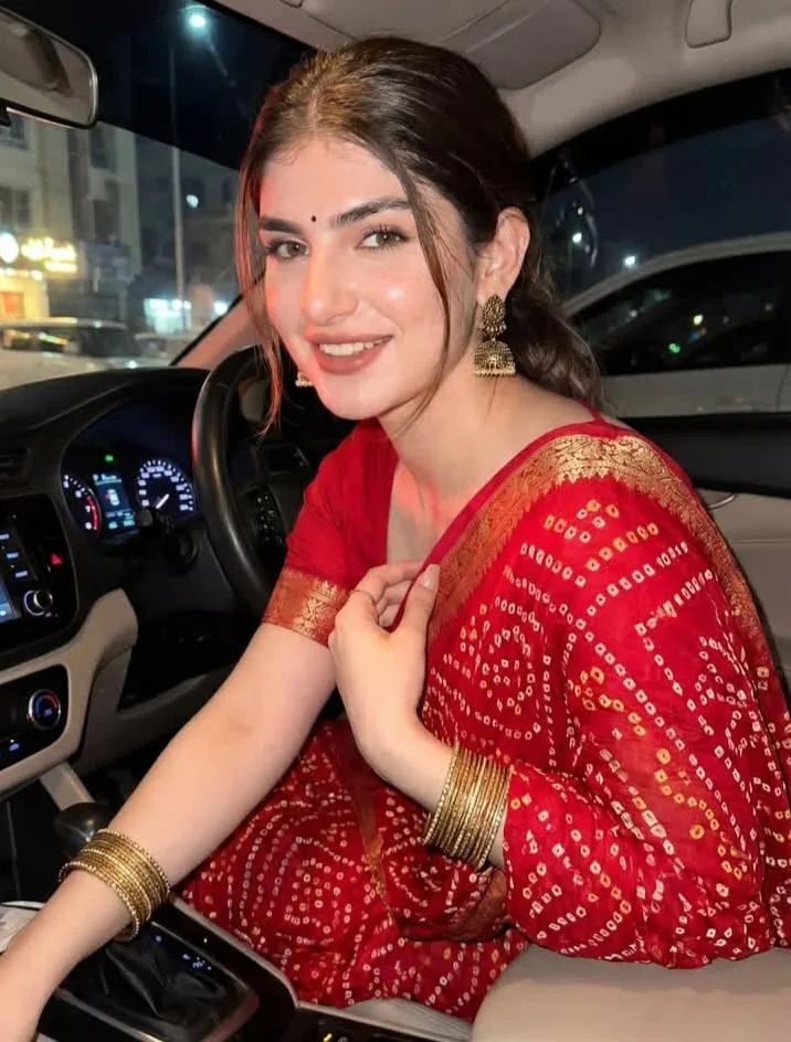 Create an ultra-realistic cinematic vertical portrait of a young Indian woman seated gracefully in the driver’s seat of a modern car at