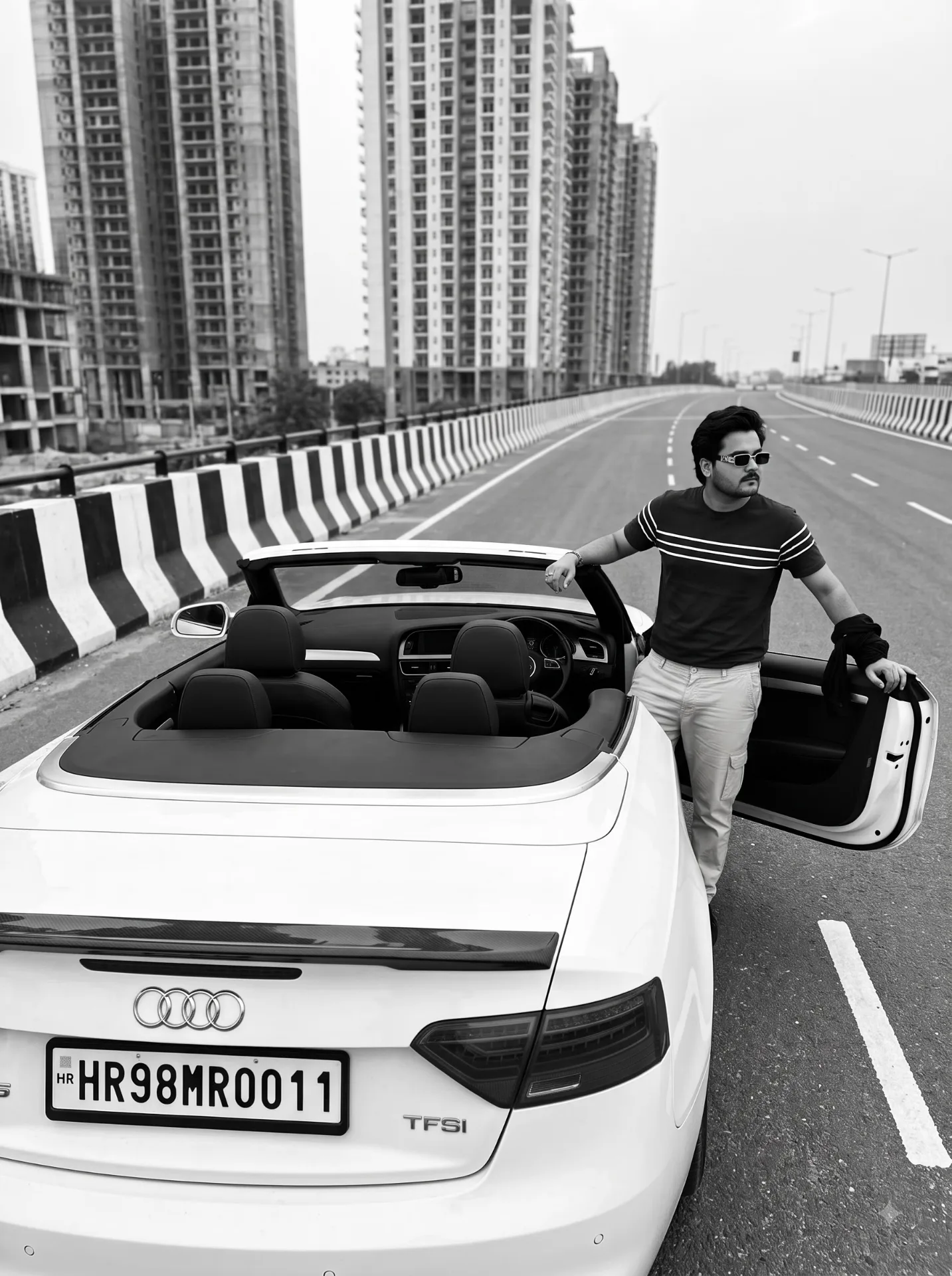Black and white cinematic photograph, rear three-quarter high angle view of a white Audi convertible S5 TFSI parked on an empty elevated