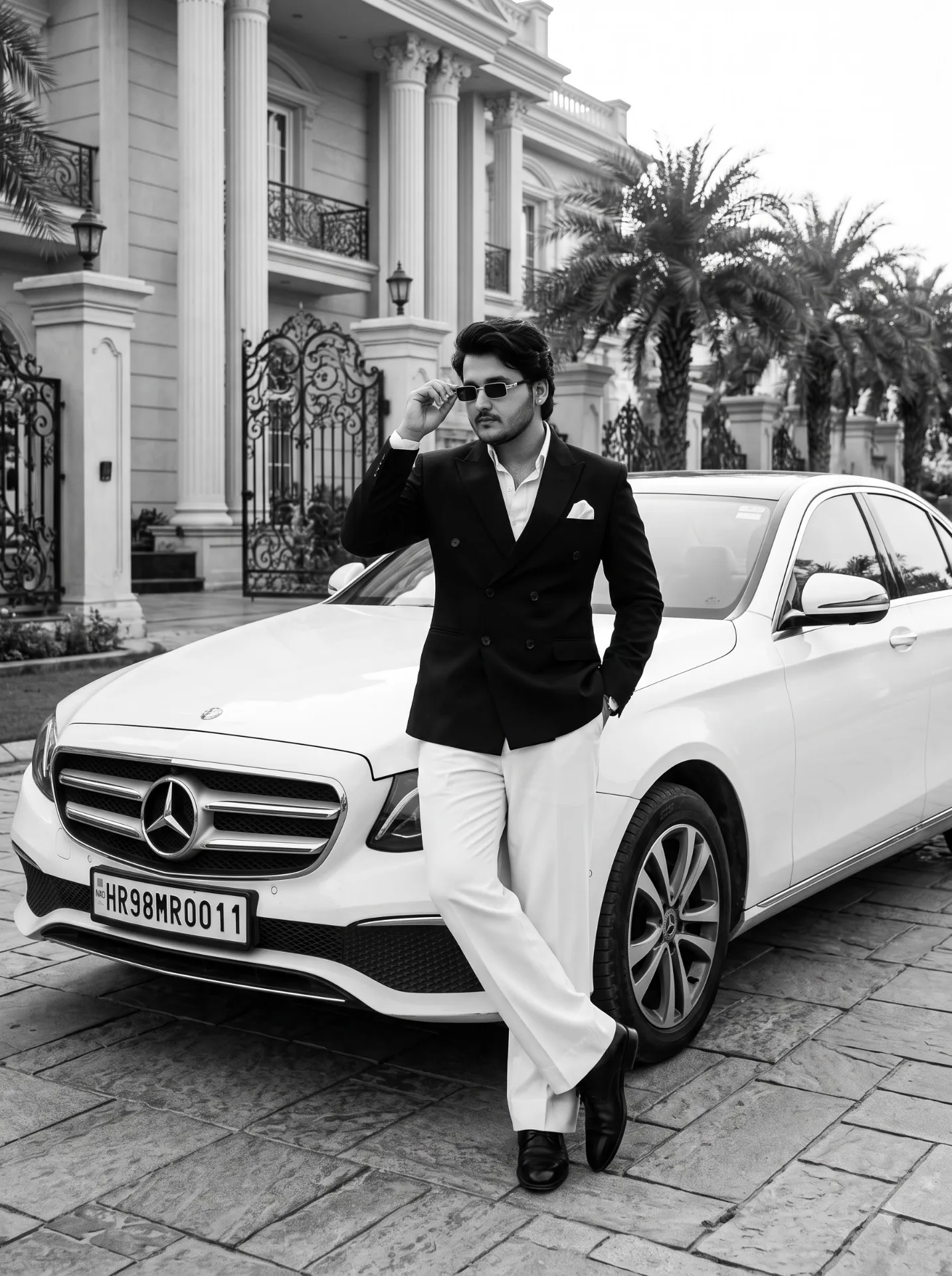Black and white editorial fashion photograph of a stylish young South Asian man with stylish black hair and a light beard, a black
