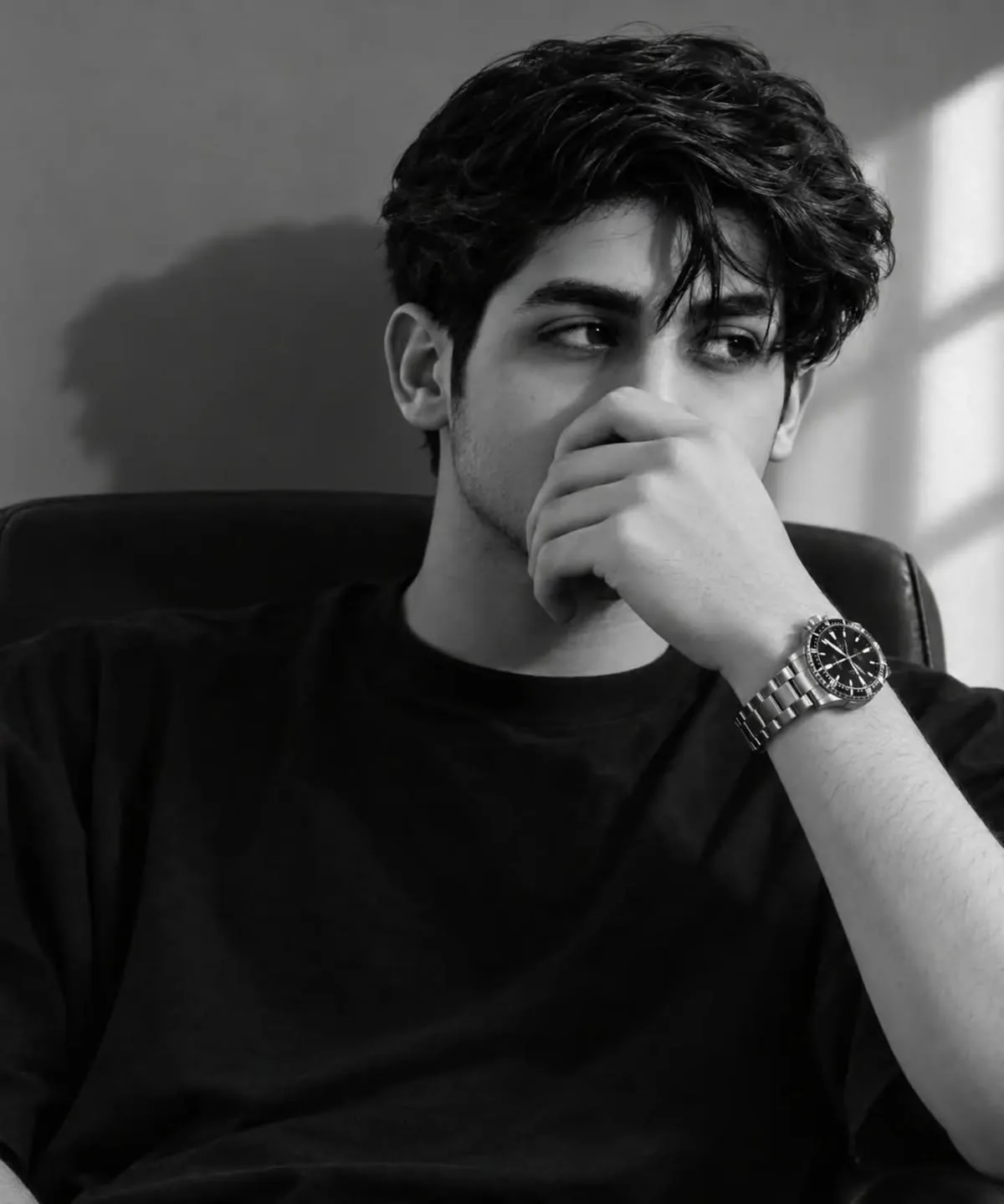 black and white cinematic portrait of a young handsome man in his early 20s, wavy textured dark hair, thick eyebrows, light stubble,