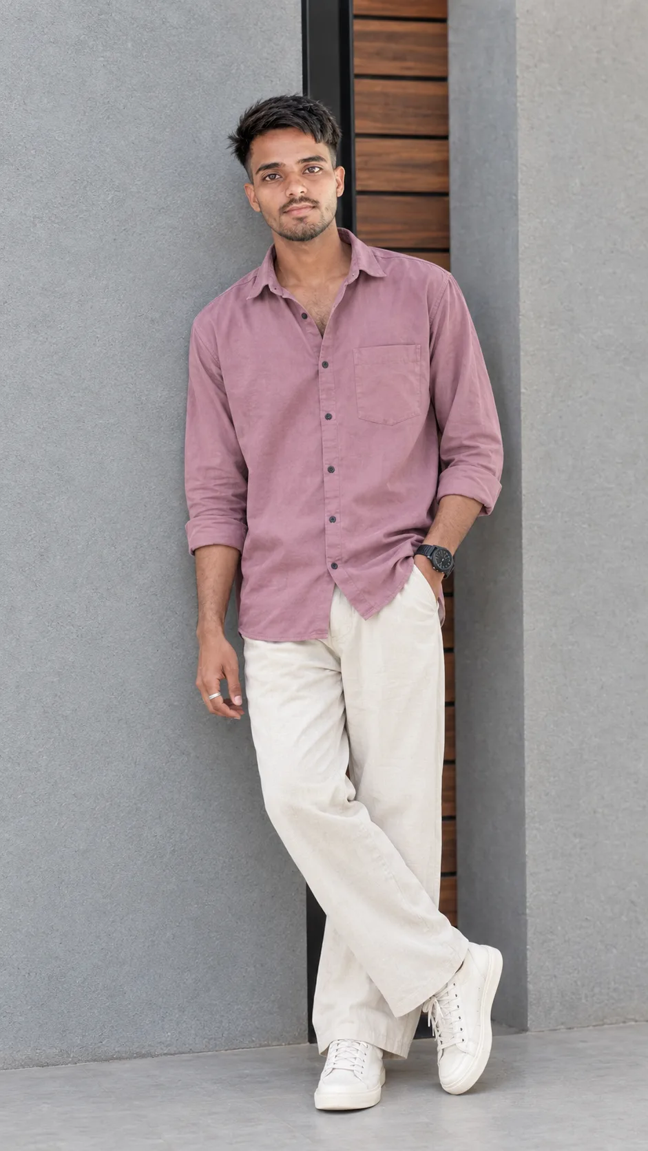 Create a highly realistic full-body fashion portrait of a stylish young South Asian/Indian man standing casually and confidently against a