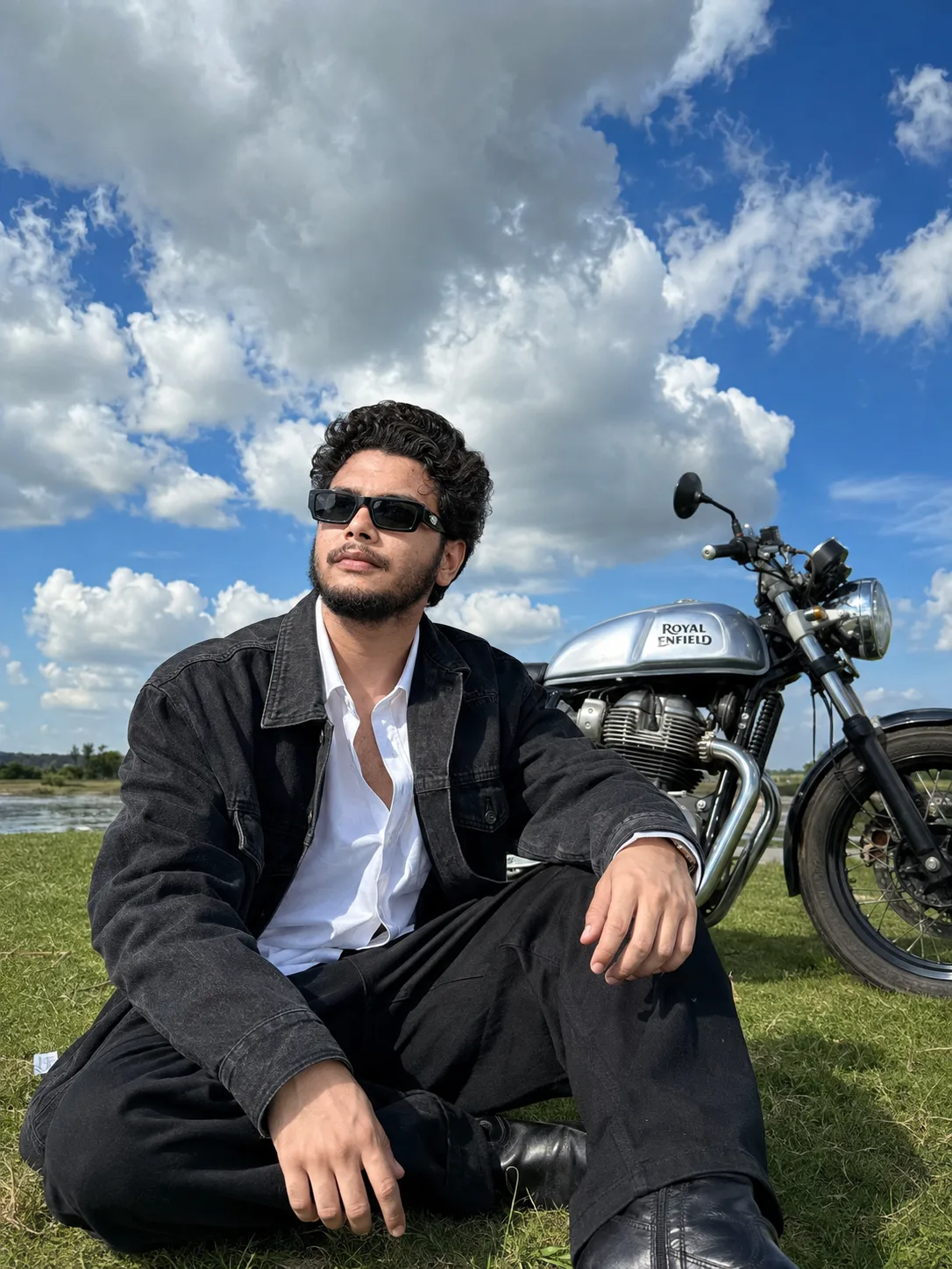 A highly realistic 8K HD high-resolution photo (3:4 aspect ratio) of a young man sitting casually on a green grassy field illuminated by