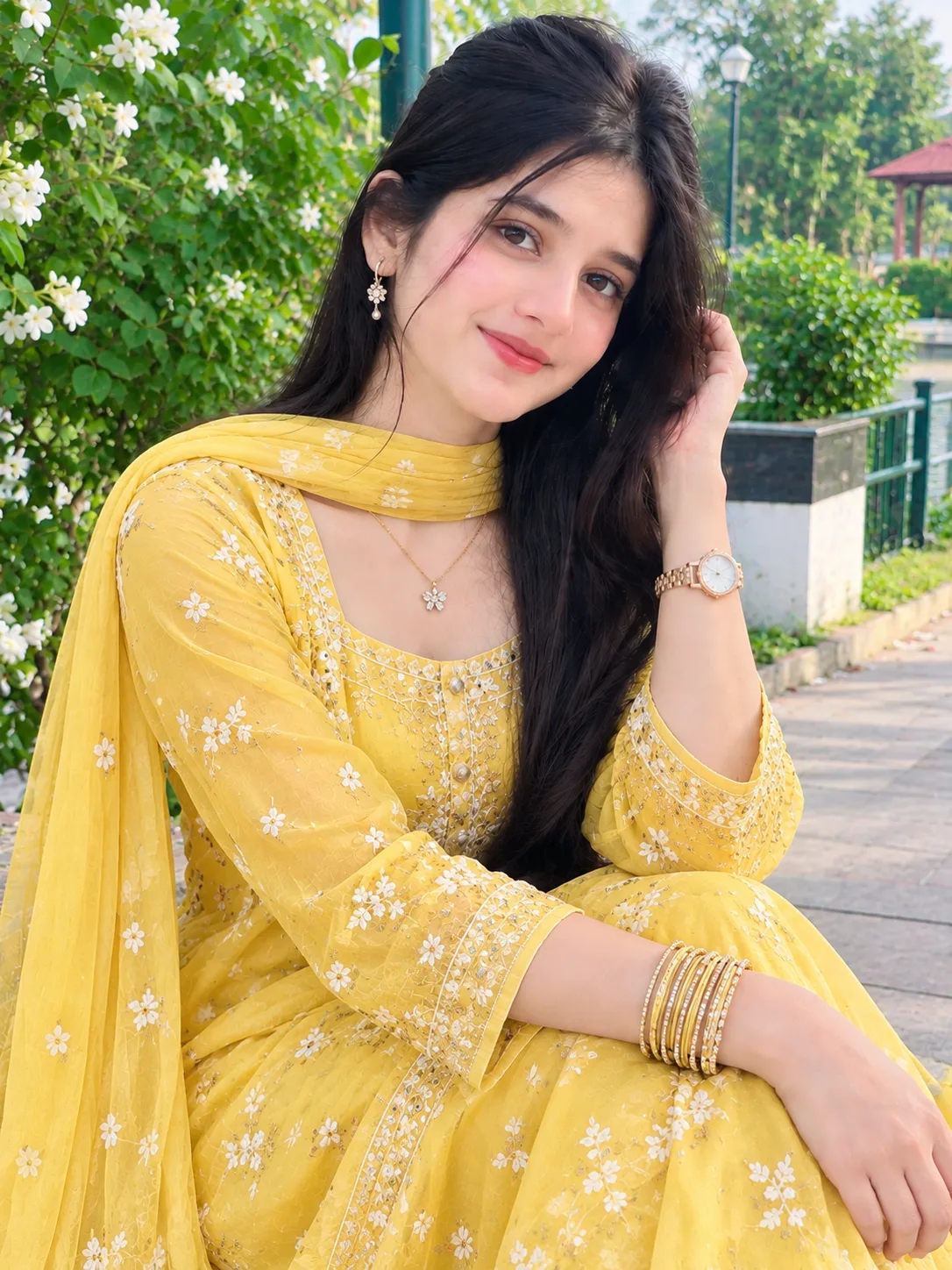 A beautiful young South Asian woman wearing a stunning golden-yellow embroidered traditional dress with matching dupatta, elegant gold