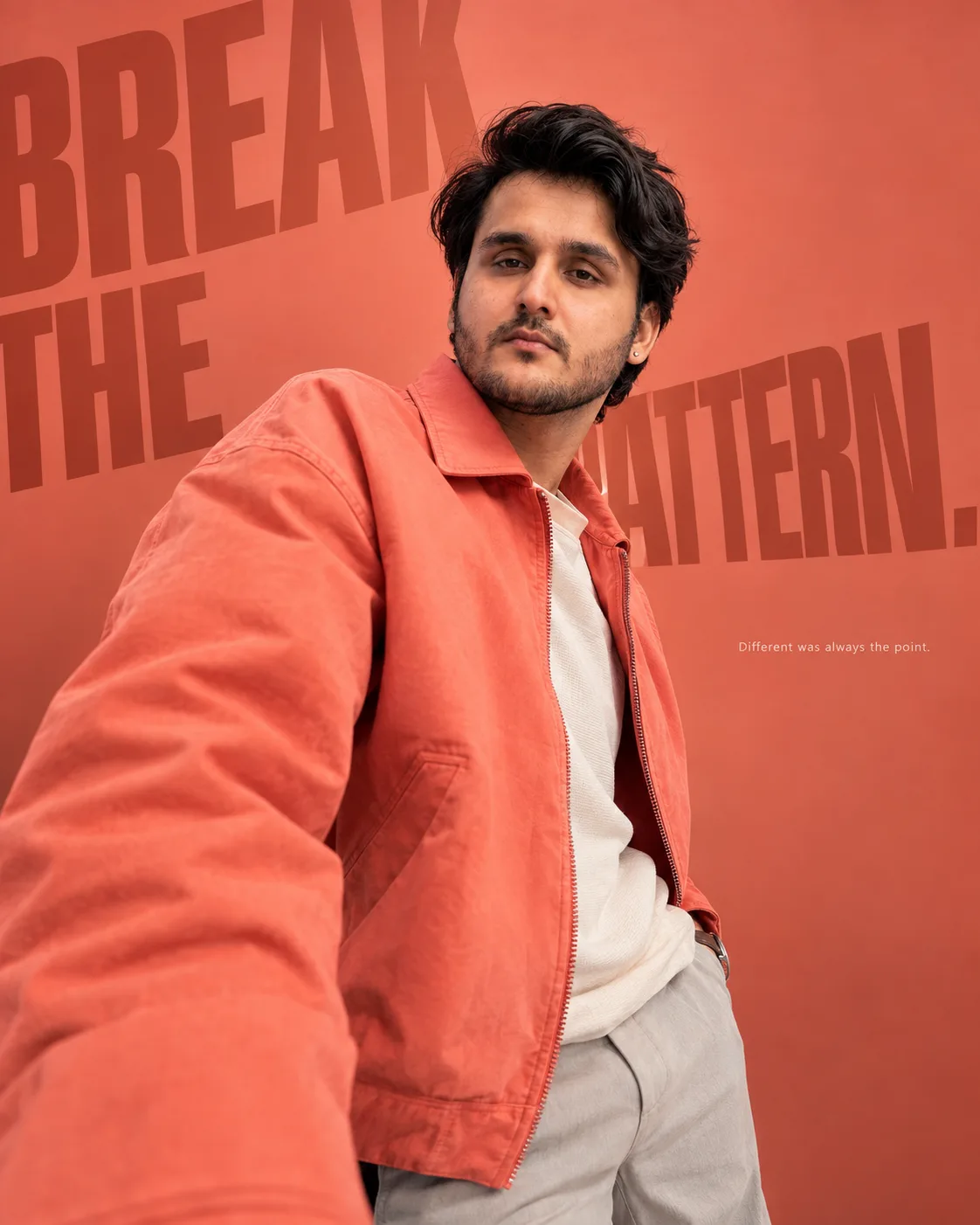 Luxury ultra-realistic fashion editorial featuring a stylish male model wearing a vivid coral jacket over a minimal contemporary outfit.