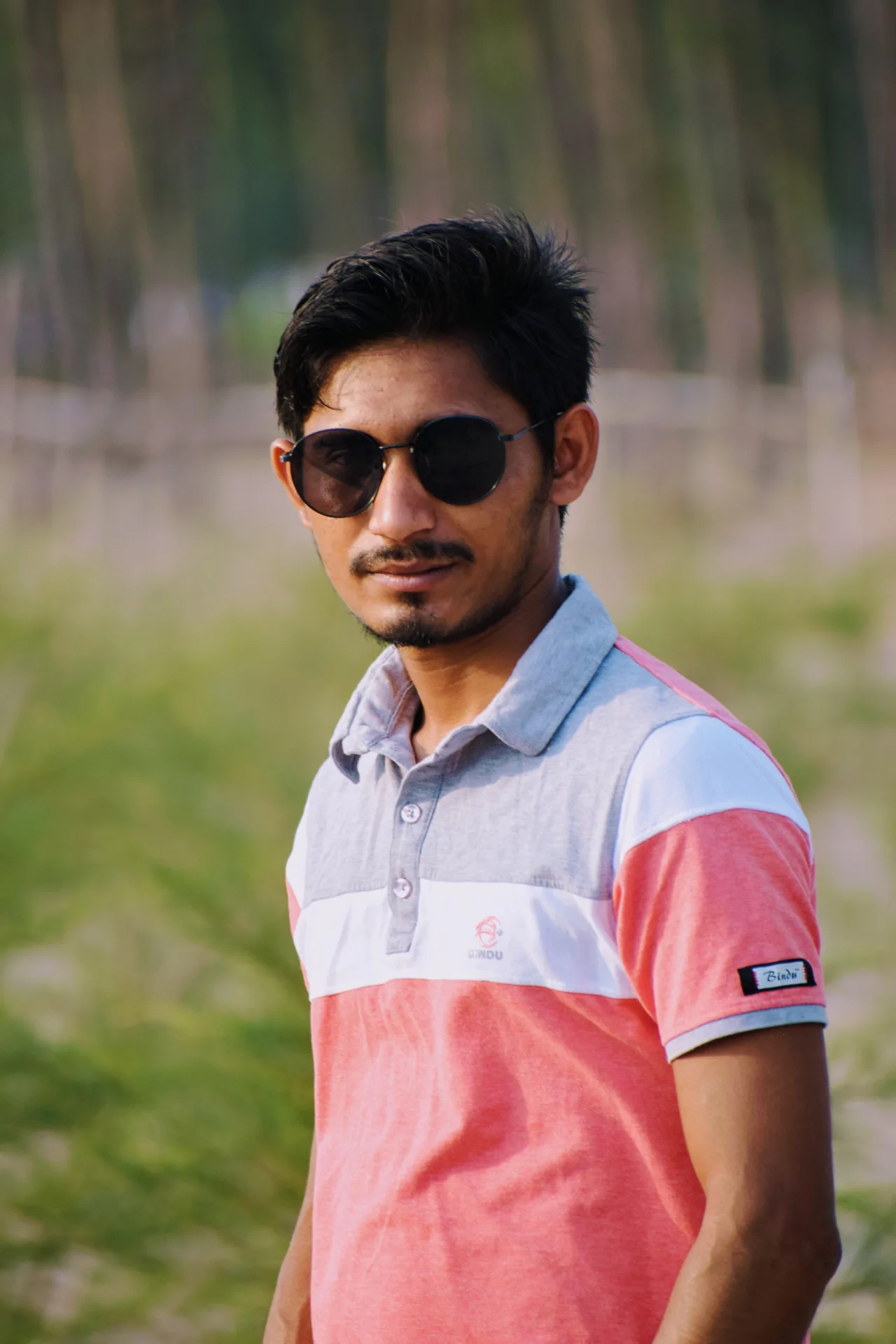 Create an ultra-realistic, high-resolution outdoor portrait of the same young South Asian man shown in the reference image.