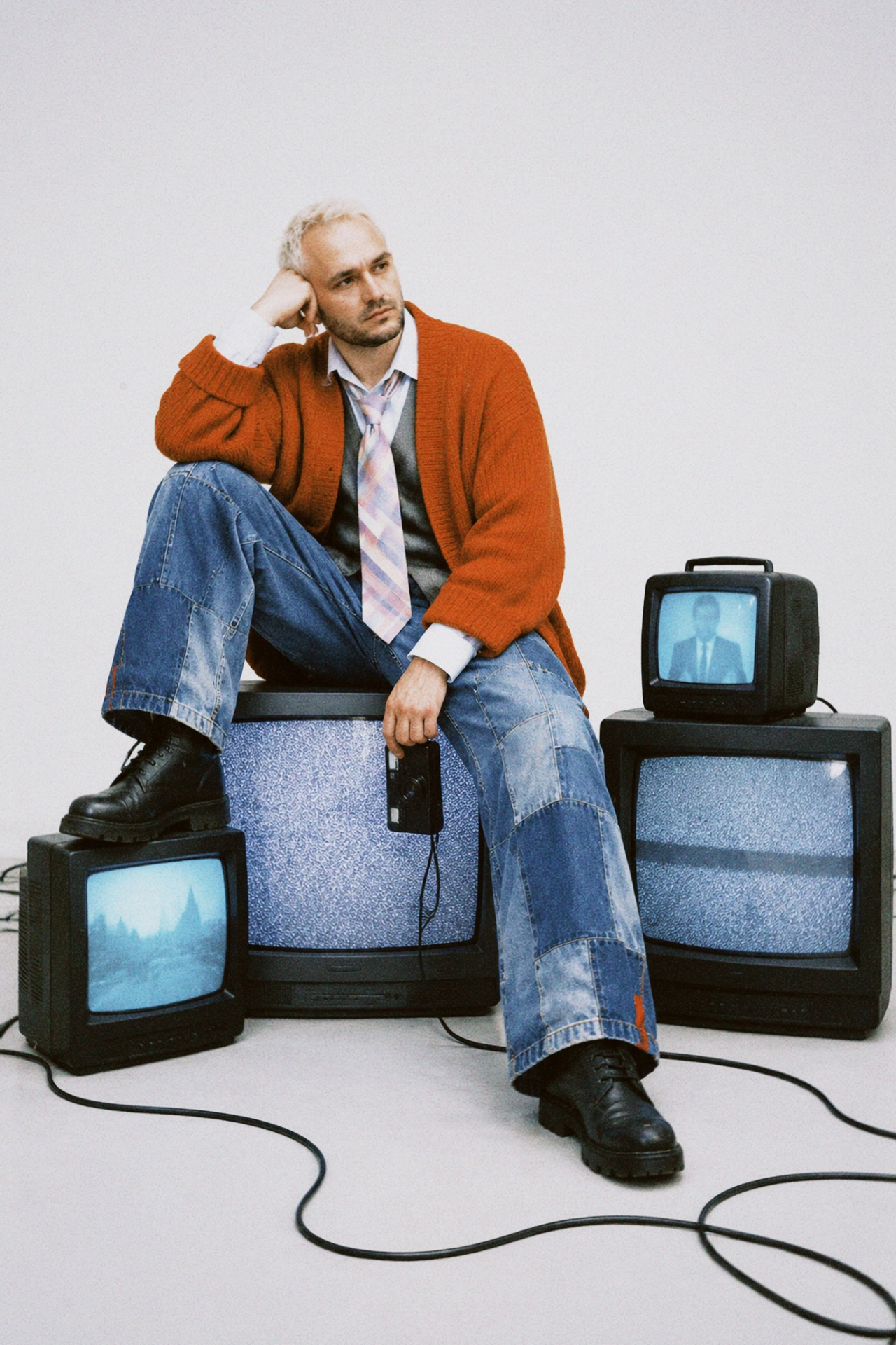 { "task": "Create a realistic studio fashion photograph of the person from the identity reference sitting among four vintage CRT