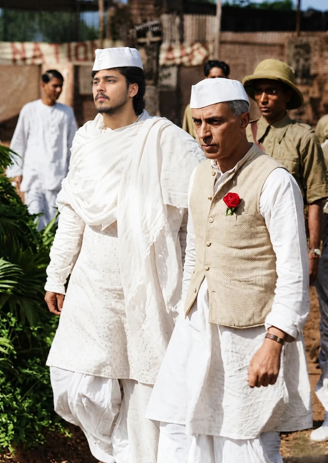 A cinematic, photorealistic historical portrait of two Indian men walking side by side through a lush outdoor setting.