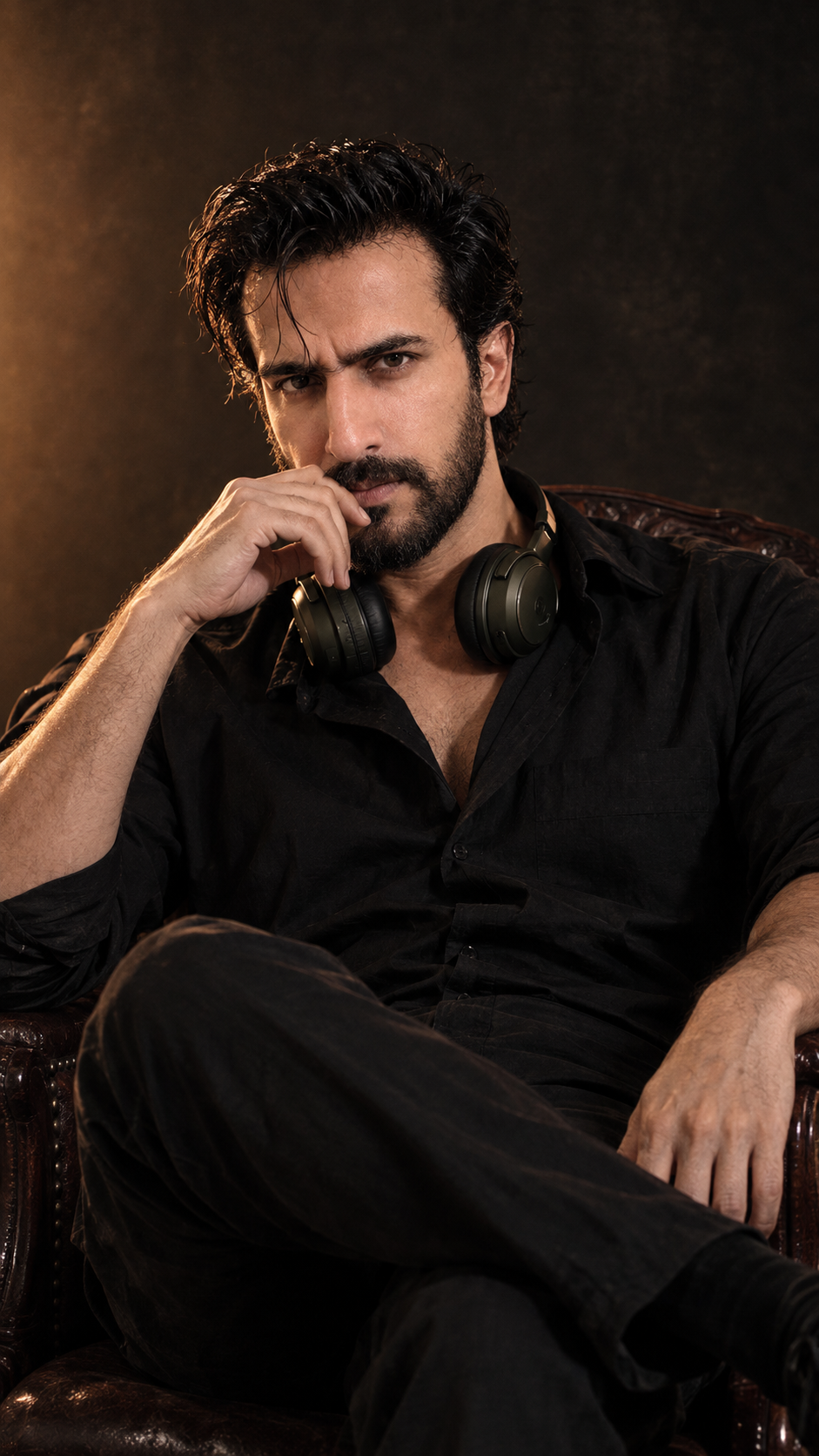 Ultra-realistic cinematic portrait of a rugged Indian man sitting confidently in a vintage wooden armchair, wearing an all-black