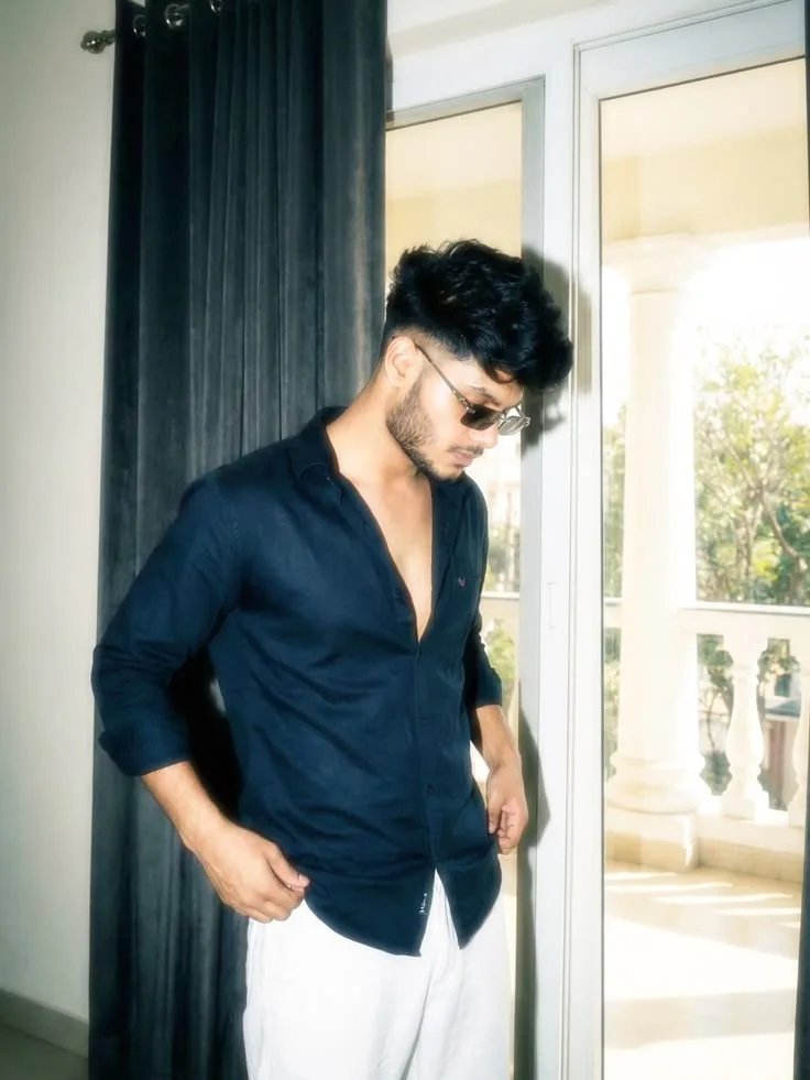 A photorealistic vertical medium shot of the young South Asian man from the reference images, faithfully preserving his exact recognizable