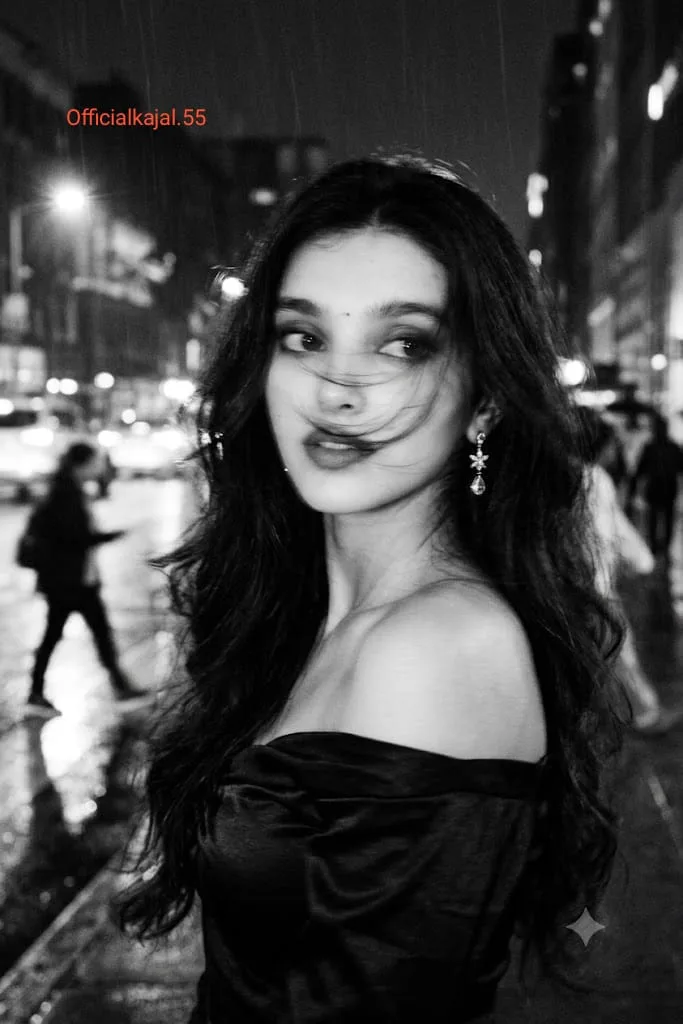 @officialkajal.55 fe A black-and-white cinematic photograph of a young woman at night in the city, shot with a long exposure and