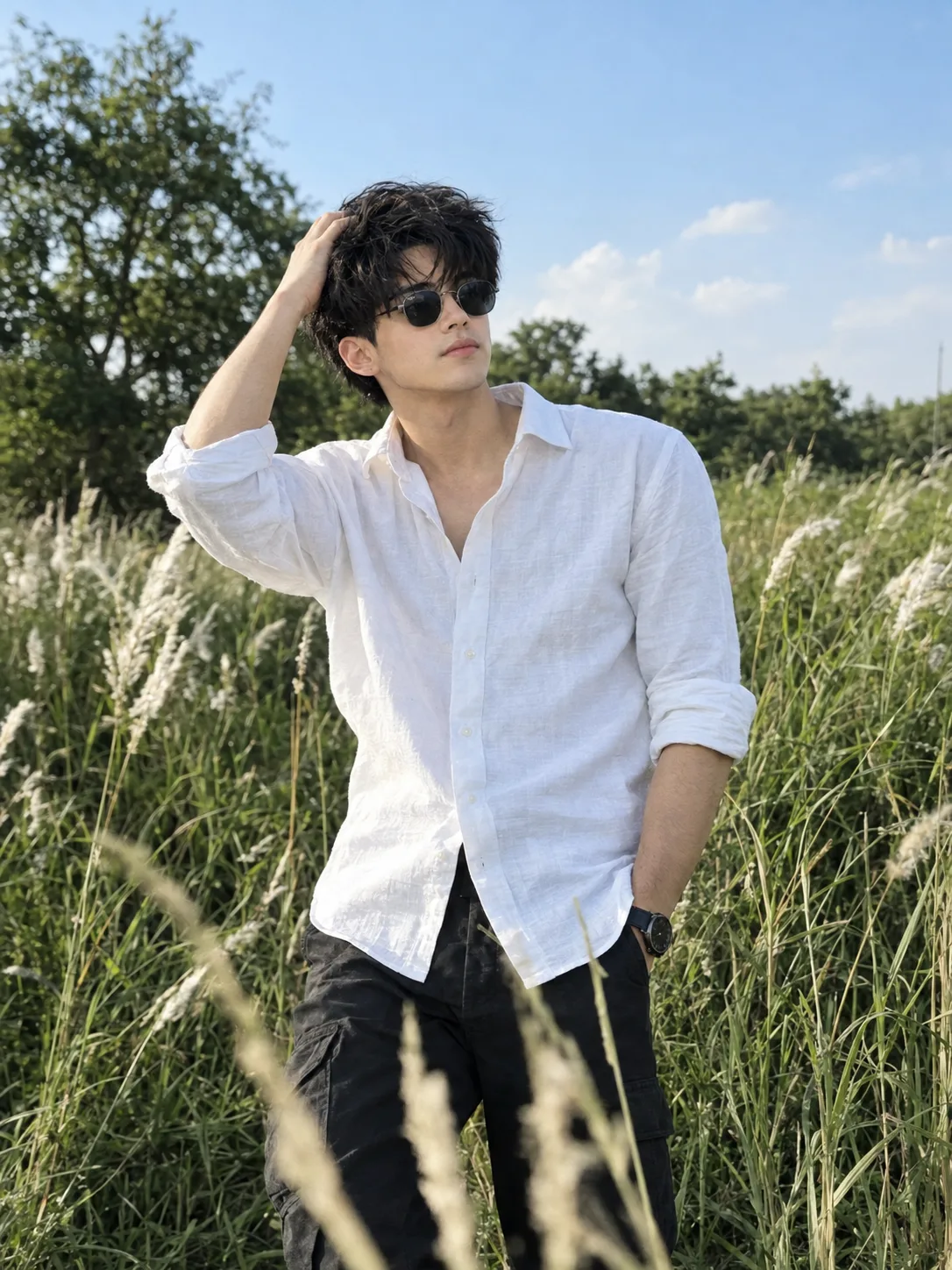 Ultra realistic photograph of a stylish young Indian man standing casually in a tall green grass field filled with soft white feathery