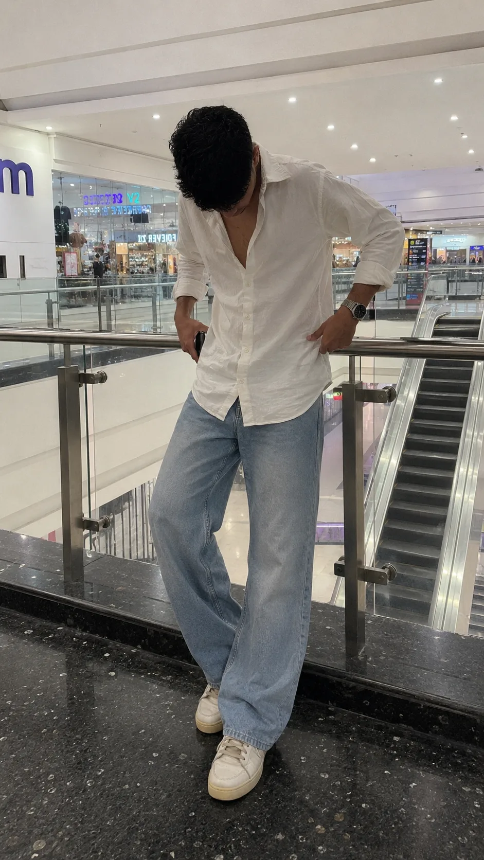 Ultra-realistic full-body fashion photo of a young male in a modern luxury shopping mall, wearing an oversized white linen shirt with
