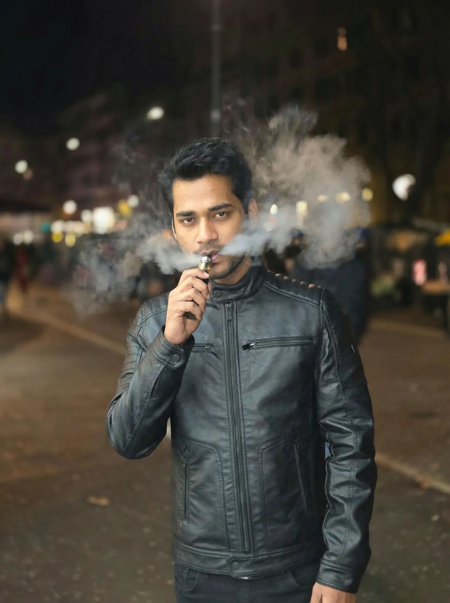 A young South Asian man with short styled black hair and light stubble, looking directly at the camera with a calm expression.