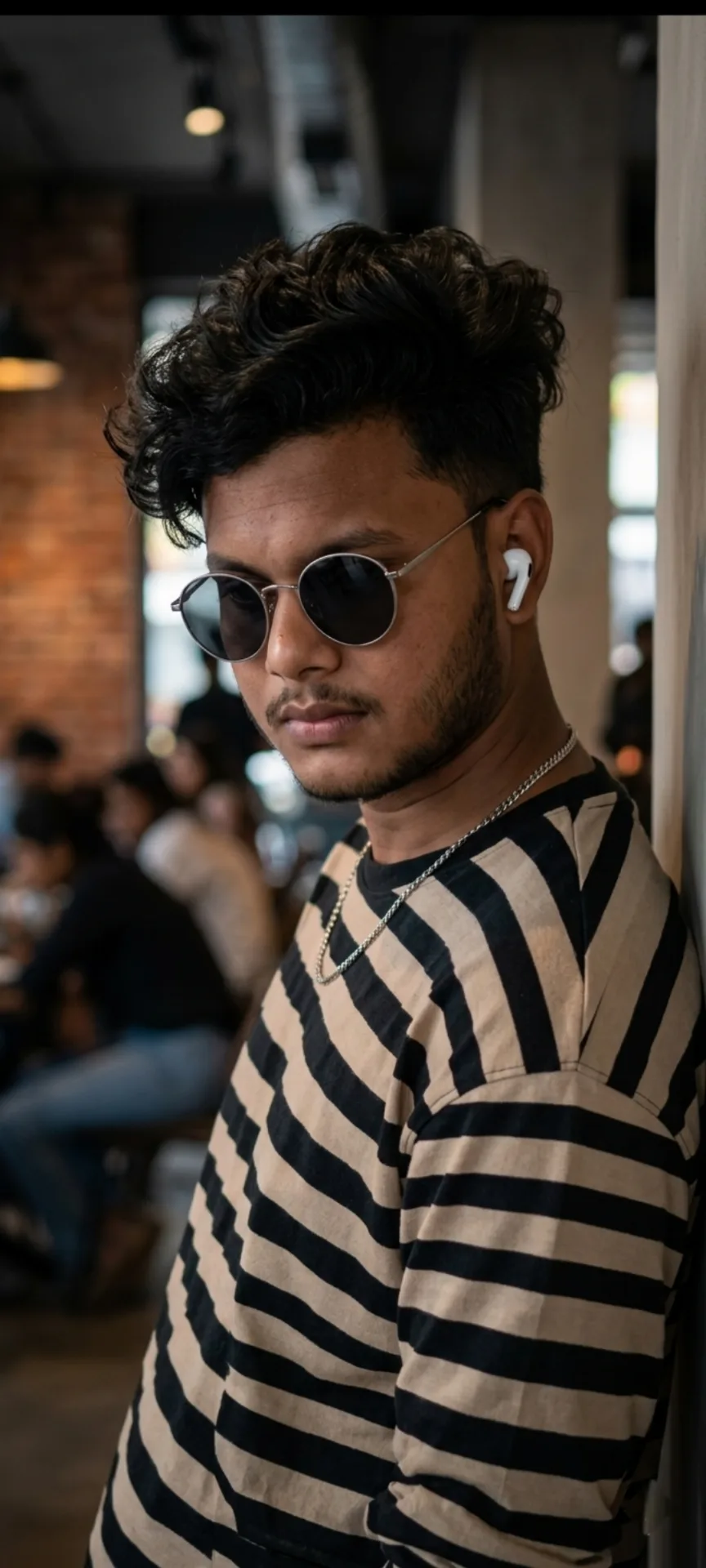 A hyper-realistic, high-definition cinematic portrait of a 26-year-old south Asian man standing inside a modern cafe or restaurant, leaning
