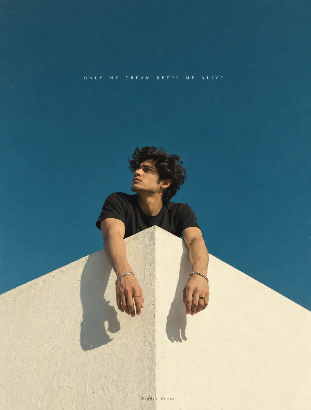 Minimalist surreal cinematic portrait of a young man leaning through the pointed peak of a stark white geometric wall, both arms hanging