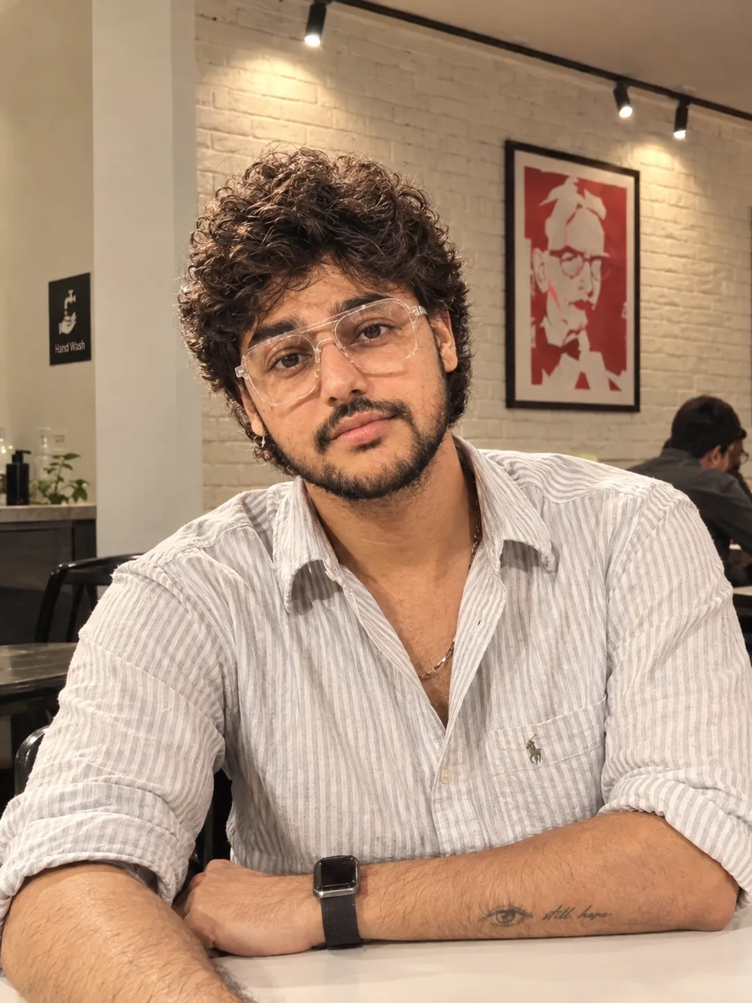 **Prompt:** "A candid portrait photo of a young man with short, soft curly dark brown hair and a neatly trimmed beard and mustache, smiling