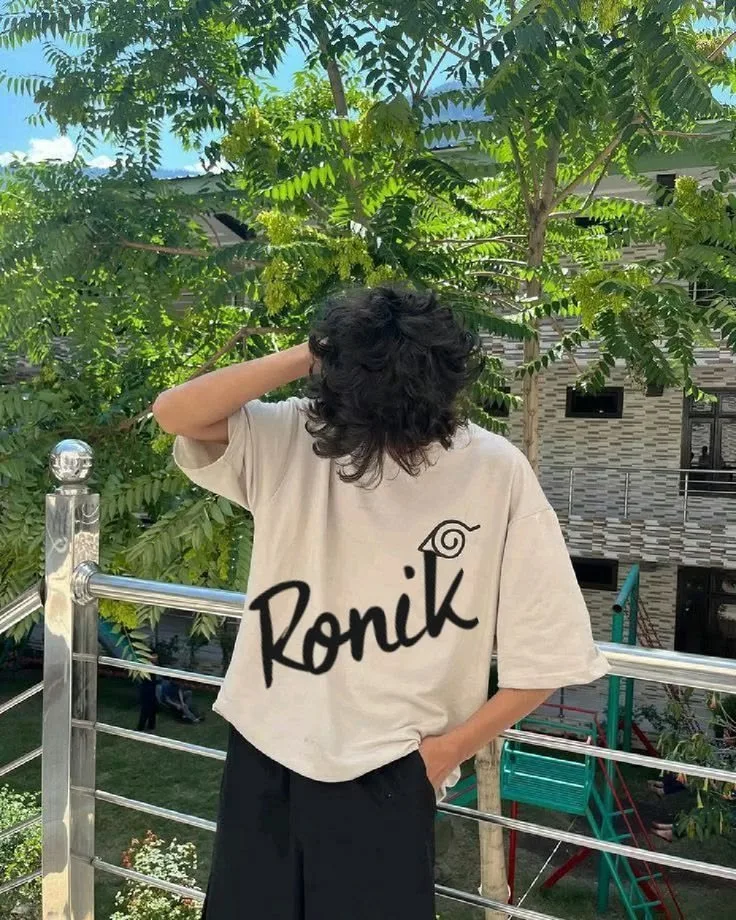 Ultra-realistic vertical 9:16 outdoor fashion portrait of a young male standing on a balcony surrounded by lush green trees.