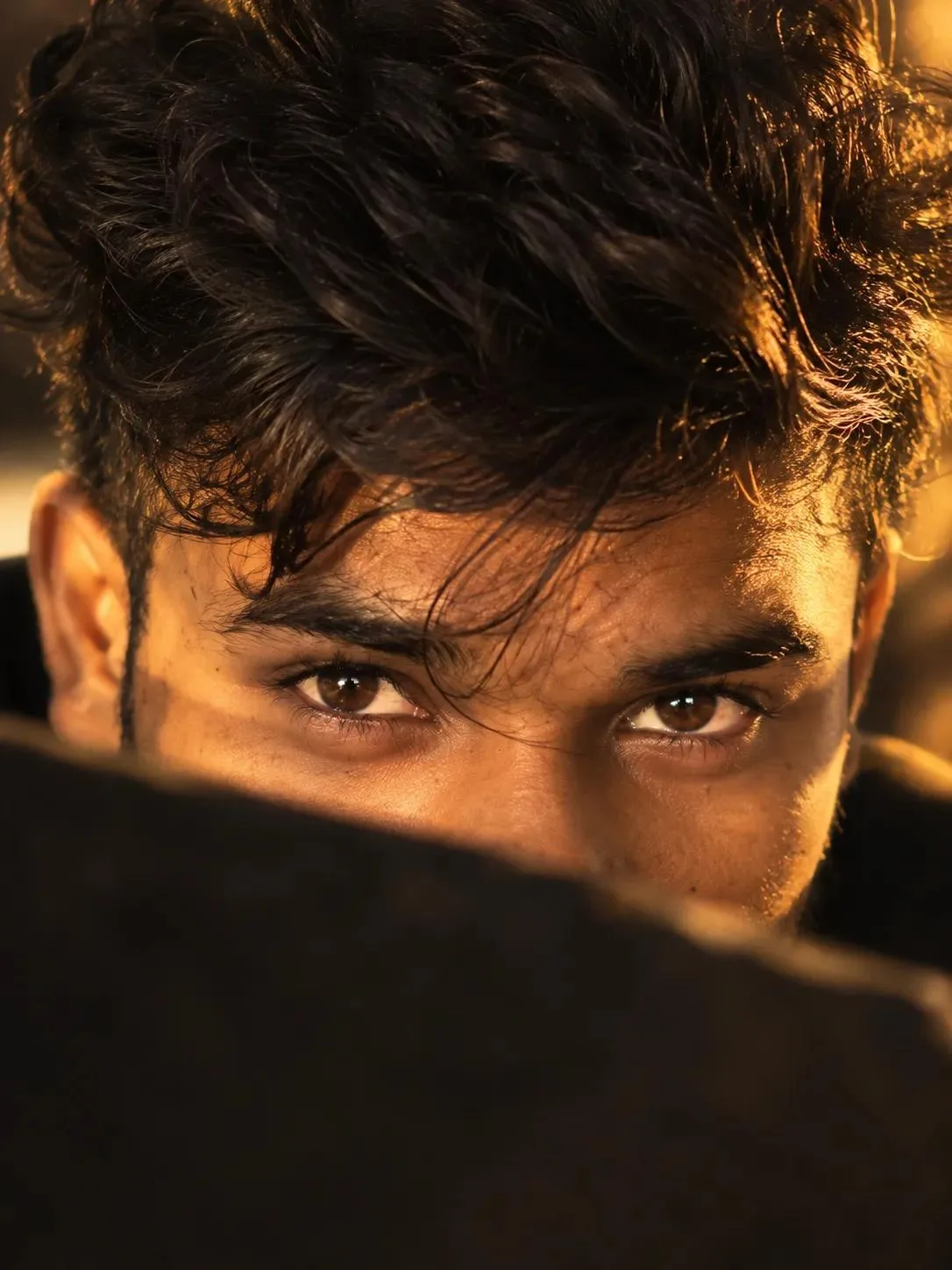 Create an ultra-realistic cinematic close-up portrait focusing on a young man's expressive brown eyes, partially hidden behind a dark