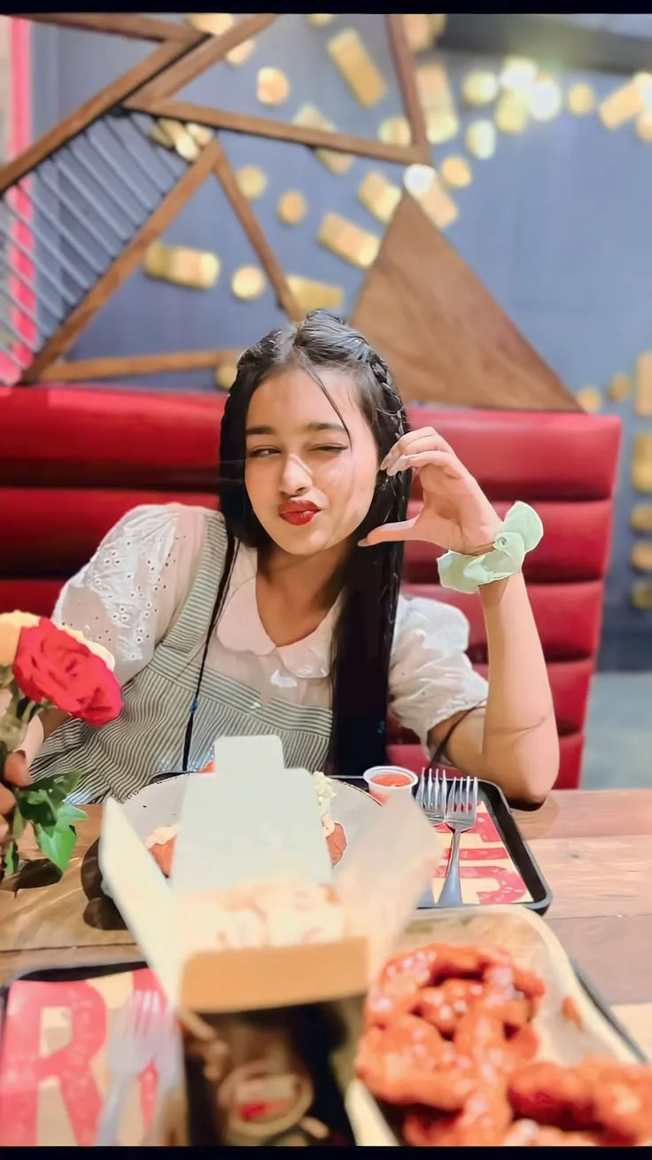 Candid Restaurant Portrait of Playful Young Indian Woman Making Heart Gesture
