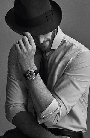 A professional black and white studio portrait of a classy man looking down.