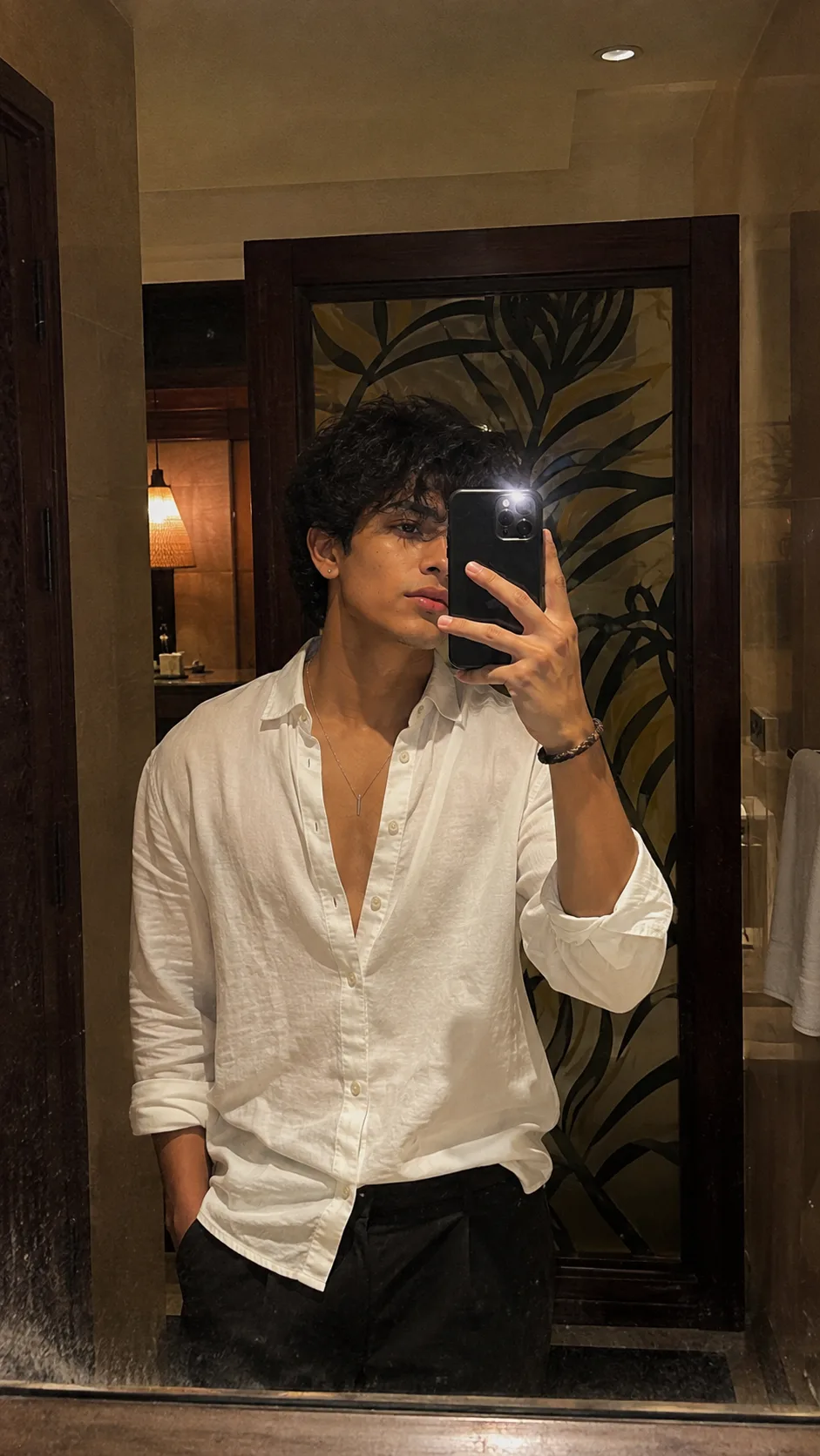 Visual Style: Ultra-photorealistic smartphone mirror selfie × contemporary menswear editorial × warm boutique-hotel interior × understated