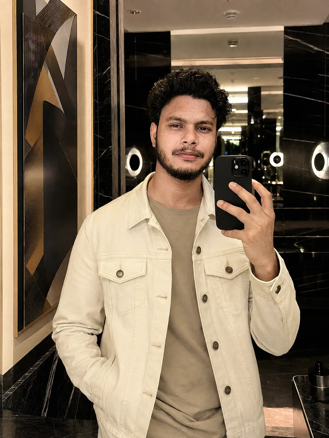An ultra-realistic luxury fashion editorial portrait of a stylish young male model taking a mirror selfie inside an upscale five-star hotel