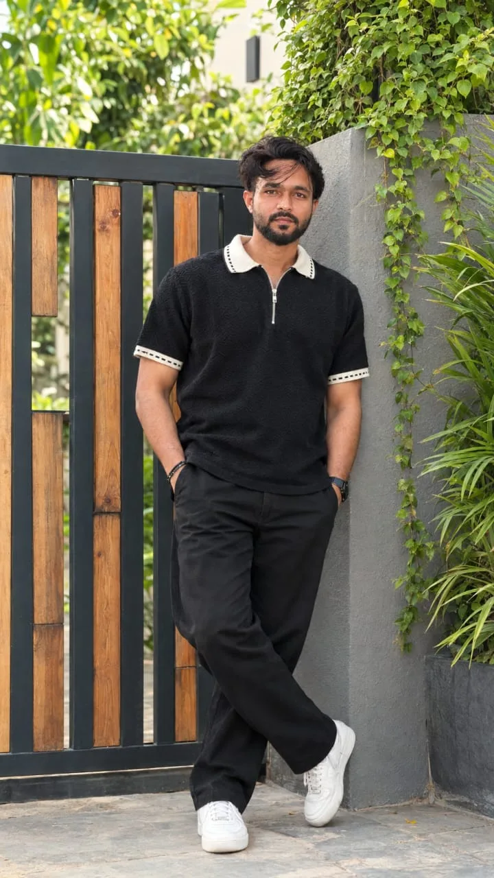 Create a highly realistic full-body professional DSLR fashion portrait of a young man standing casually beside a modern gray textured wall