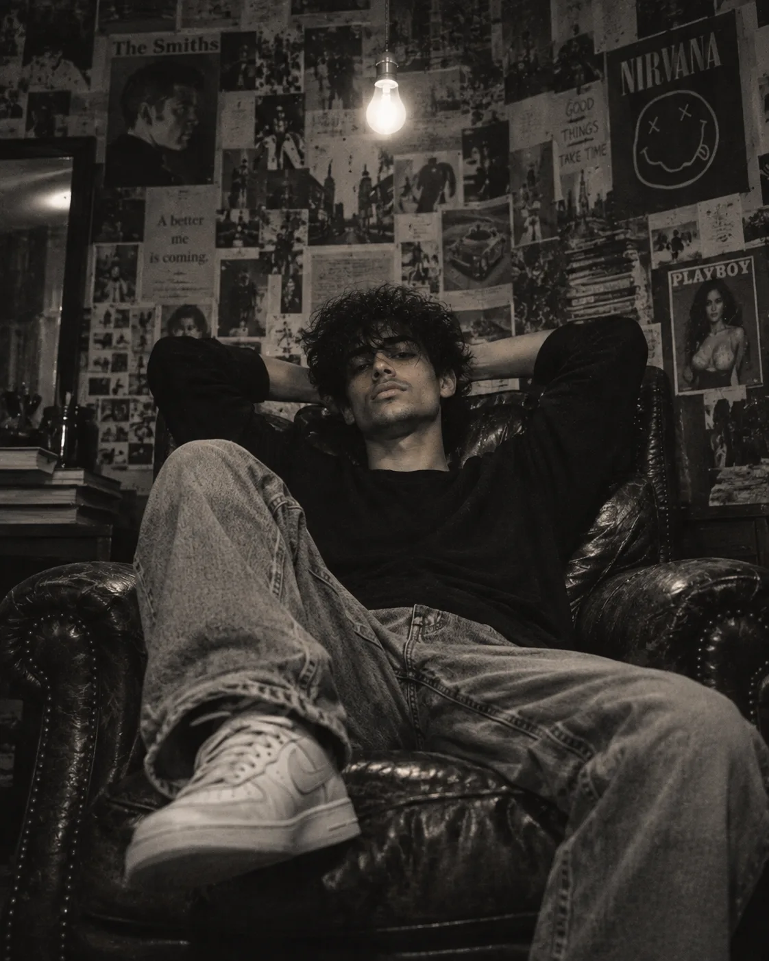 Create an ultra-realistic cinematic black-and-white editorial photograph of a young man relaxing deep inside a vintage dark leather