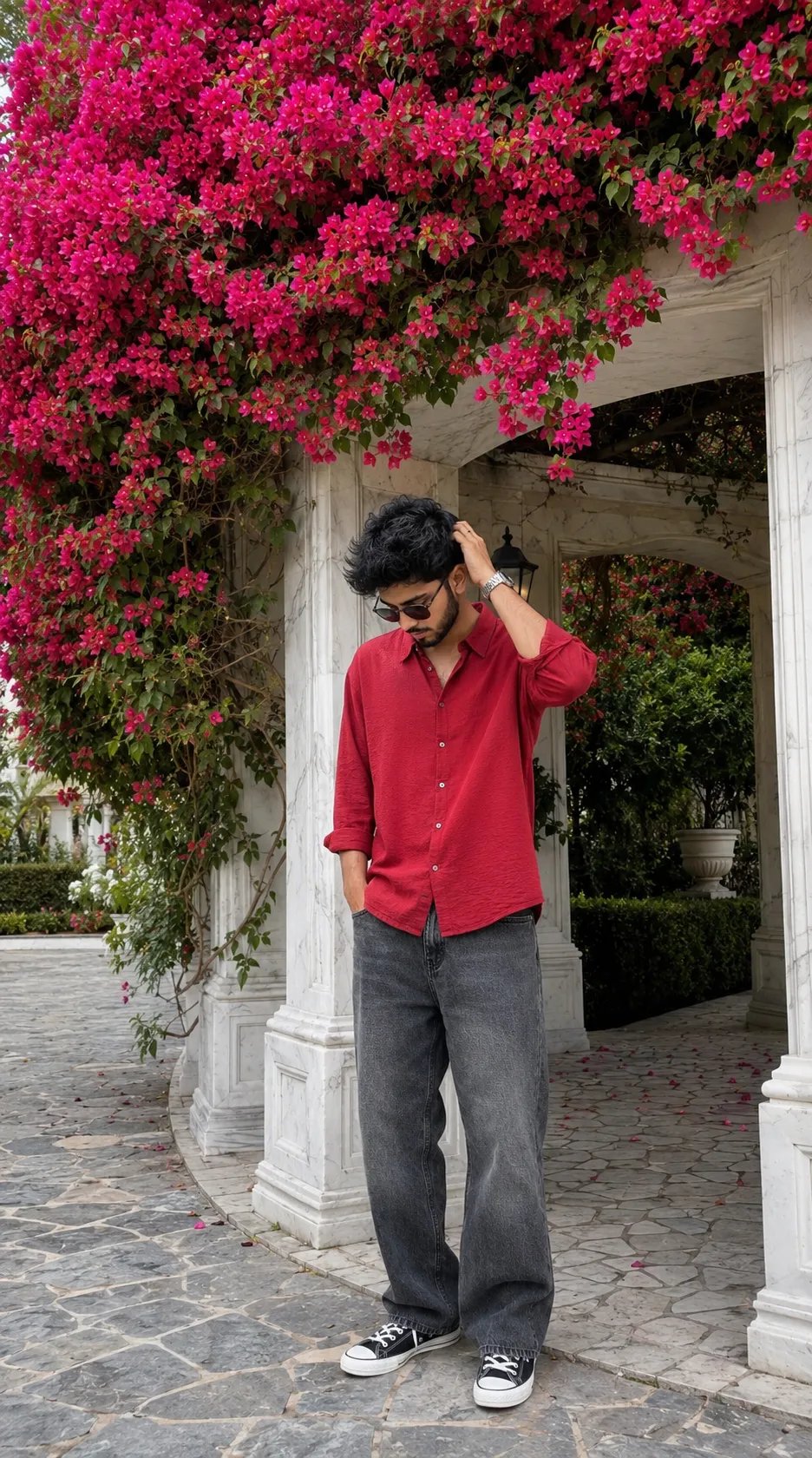 Ultra-realistic iPhone portrait photo of a young manstanding under a large white marble structure and bougainville filled with dense