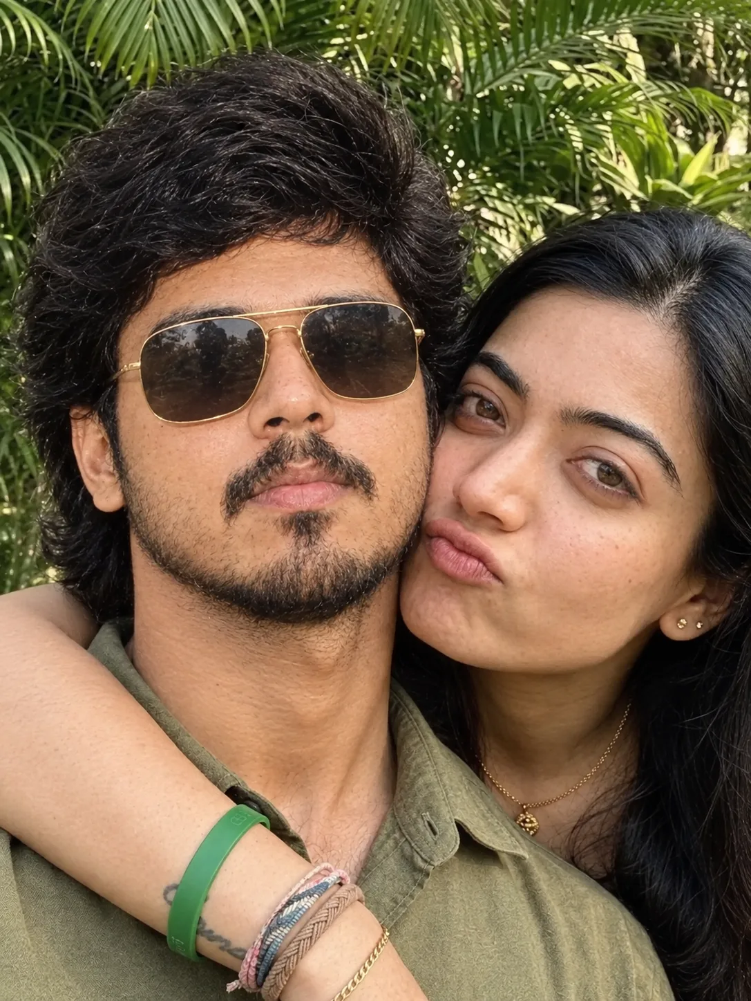 Create an ultra-realistic close-up outdoor couple selfie in a lush tropical garden, using the uploaded image as the composition and pose