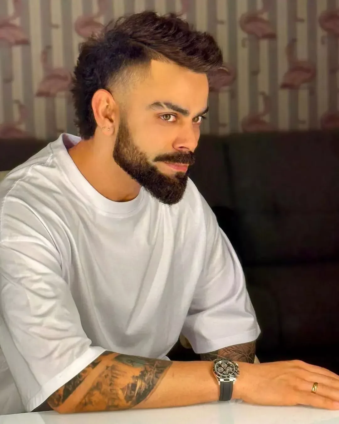 > Ultra-realistic cinematic portrait of a young man sitting casually at a table, wearing an oversized plain white crew-neck T-shirt.