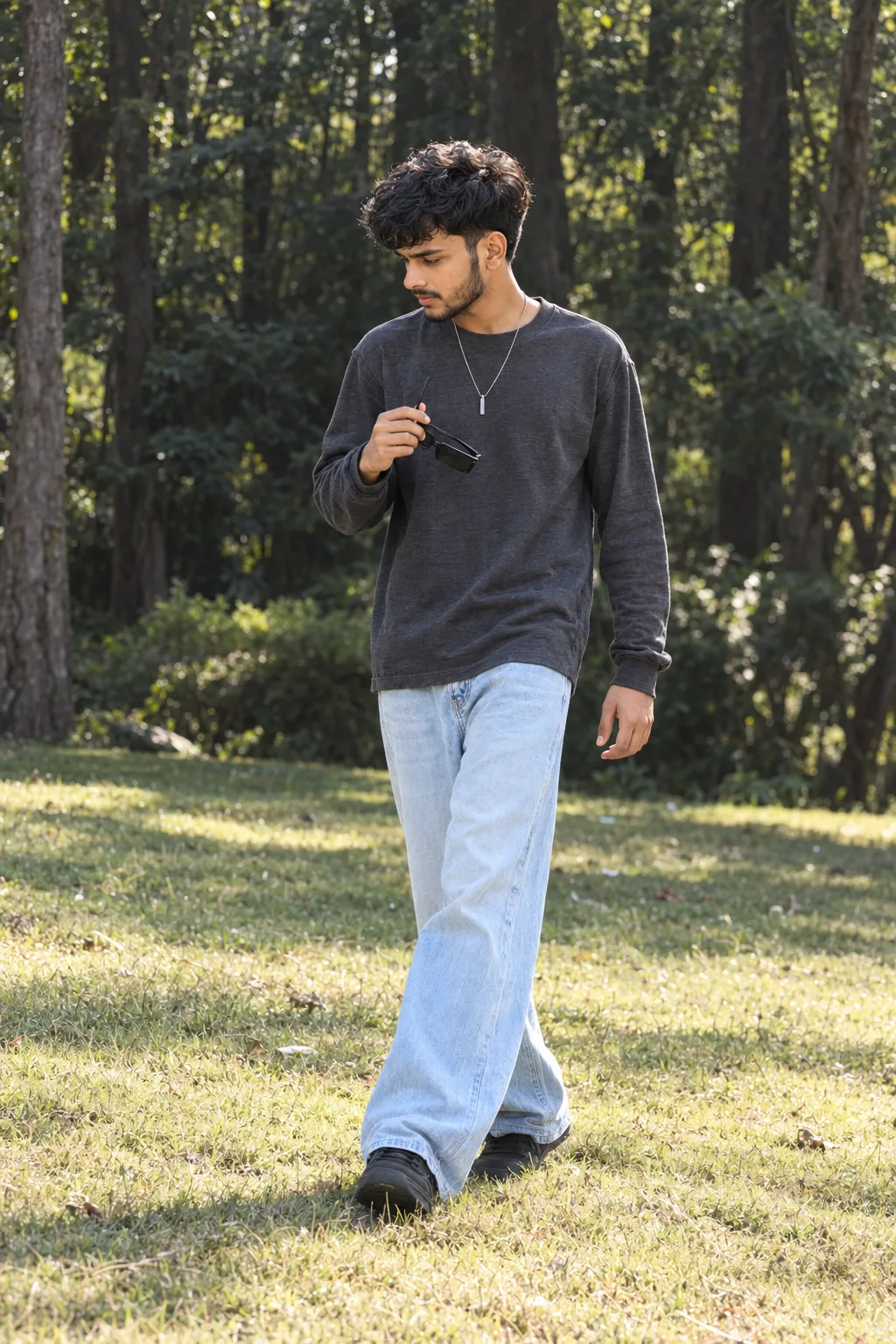 Ultra-realistic professional DSLR photograph of a slim young South Asian man walking naturally across a sunlit grassy field in a wooded