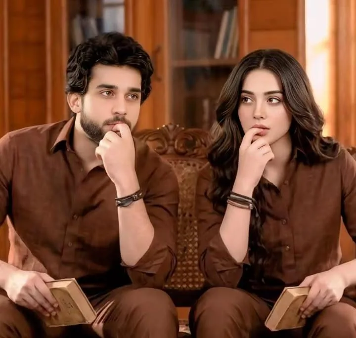 A highly detailed, photorealistic medium shot portrait of an attractive young South Asian couple sitting side-by-side on an elegant vintage