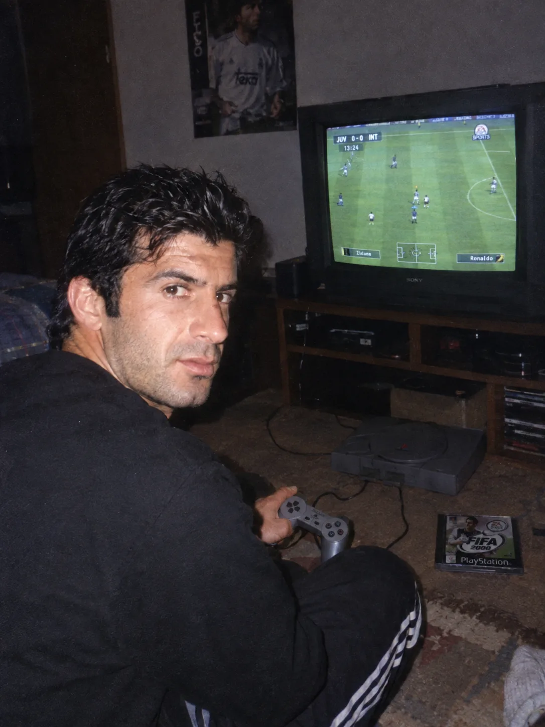 Grungy analog photo of Luis Figo circa 2000 playing Fifa 2000 on Playstation 1 on a 90s CRT TV in a dimly lit bedroom.